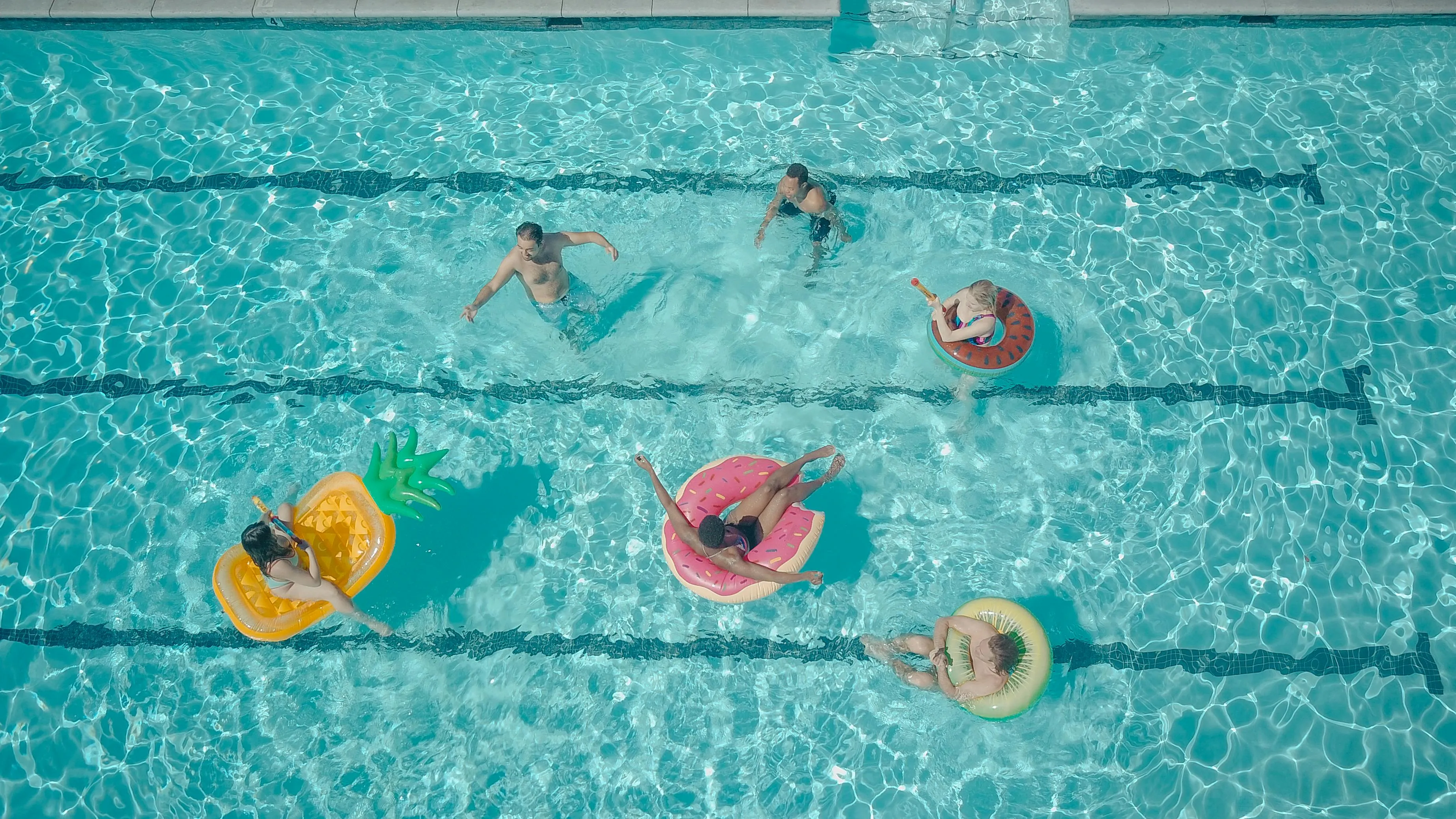People enjoying a pool day on various floaties and swimming, reflecting a playful courage meter in water activities.