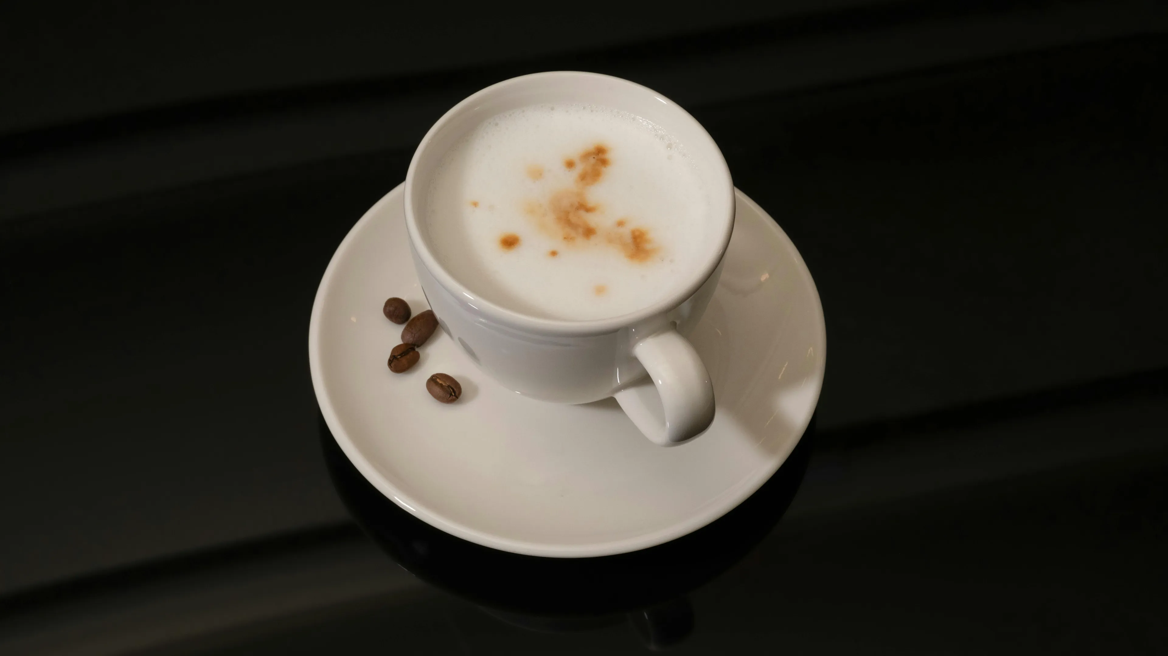 Cup of coffee with foam and coffee beans on a white saucer, illustrating courage meter coffee order choices.
