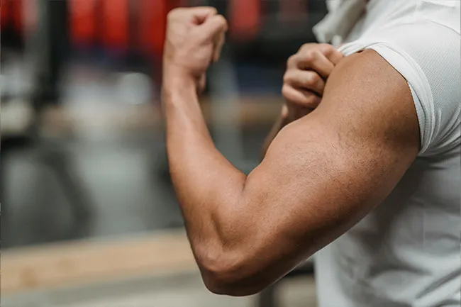 Person flexing a muscular arm in a short sleeve shirt, symbolizing super strength as a desired superpower.