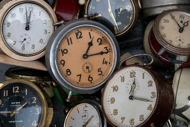 Collection of vintage clocks showing different times, symbolizing the concept of time travel superpower choice.