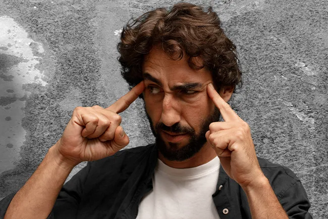 Man concentrating deeply with fingers on temples, illustrating mind reading as a superpower concept.