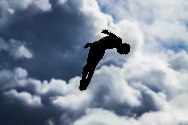 Silhouette of a person midair against cloudy sky, depicting the superpower of flight in dramatic contrast.