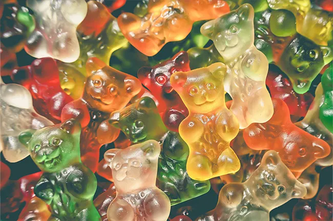 Close-up of colorful gummy bears piled together, showcasing a variety of translucent red, green, yellow, and orange candies.