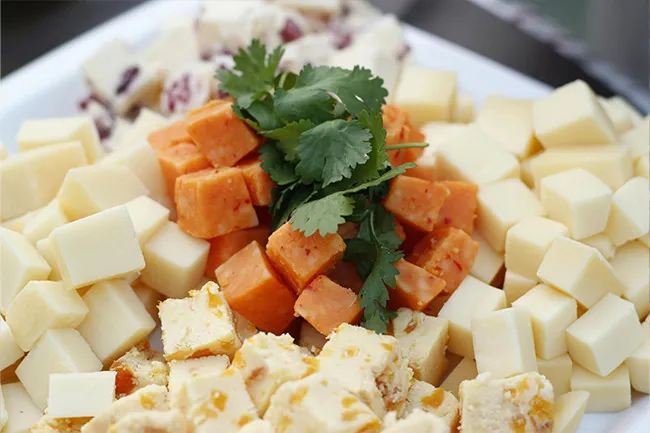 Assorted cheese cubes on a white plate with fresh herbs as a savory nervous snack choice.