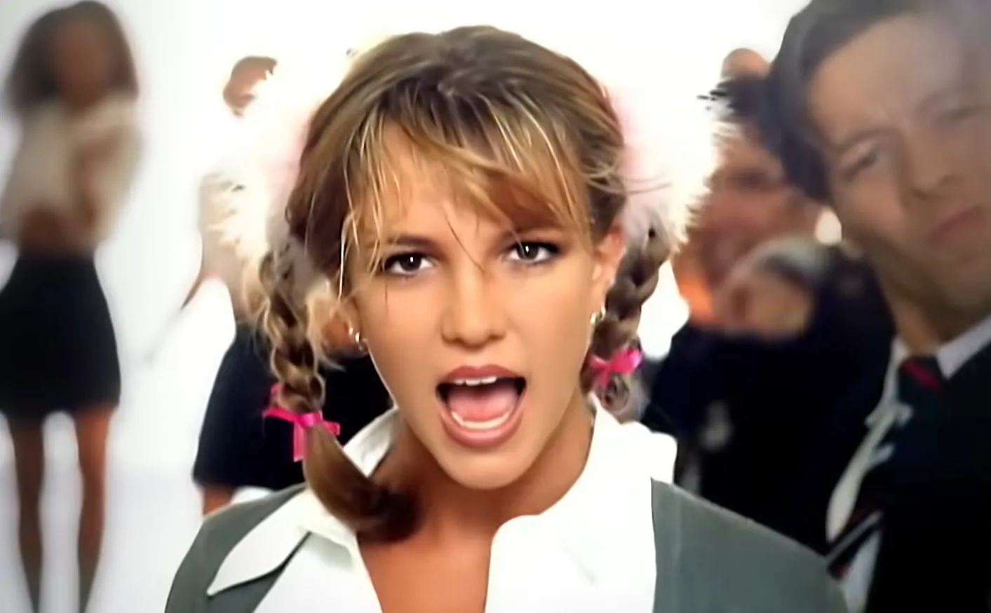 Famous '90s music icon performing with braided hair and school uniform inspired outfit in a high-energy music video.