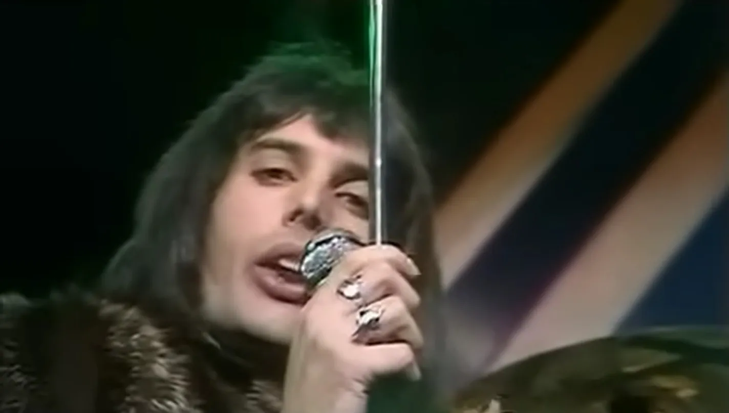 Freddie Mercury performing on stage, close-up holding a microphone, representing '80s and '90s music icons.