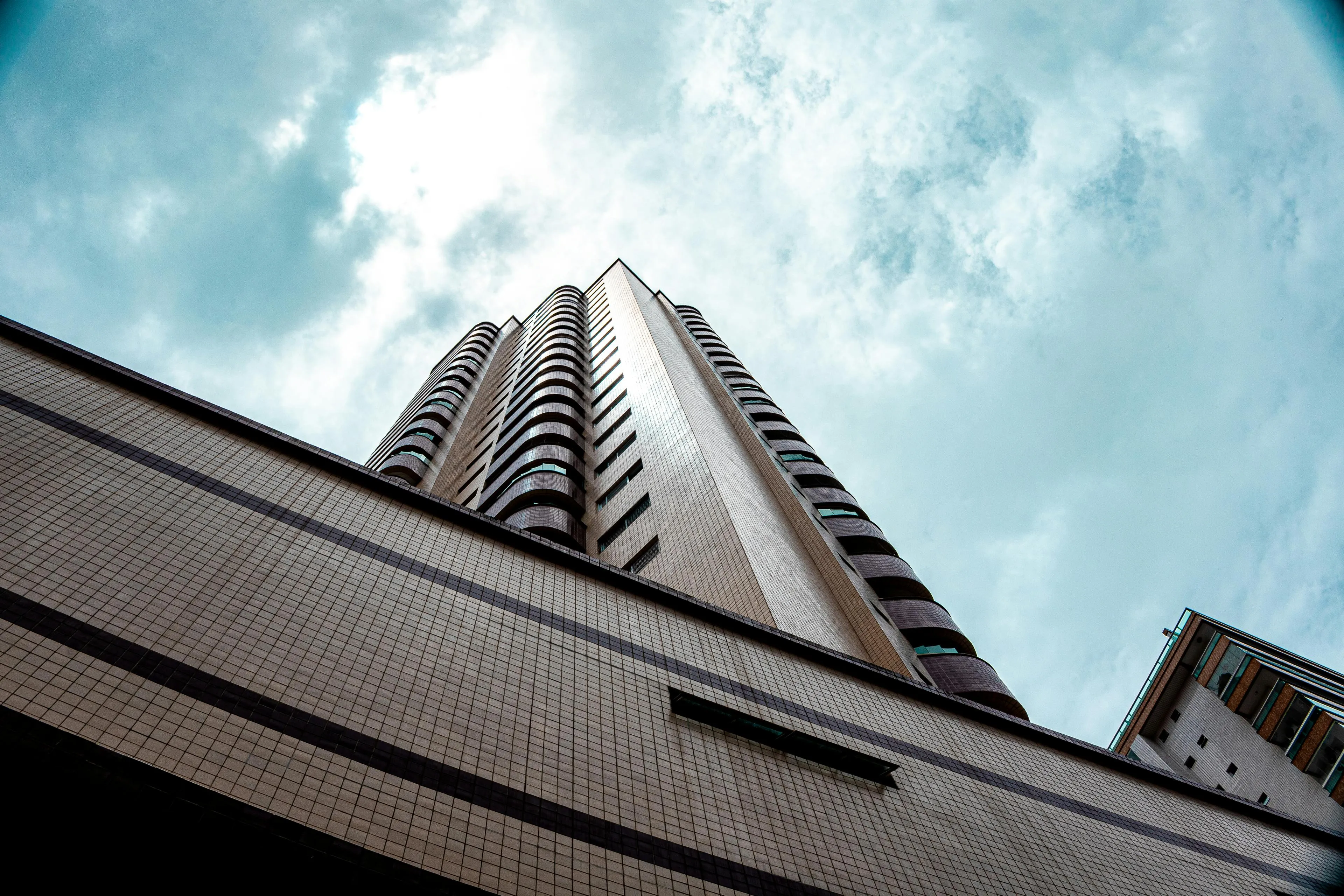 Looking up at a tall modern building with balconies under a cloudy sky, featuring the tallest building in the world concept.