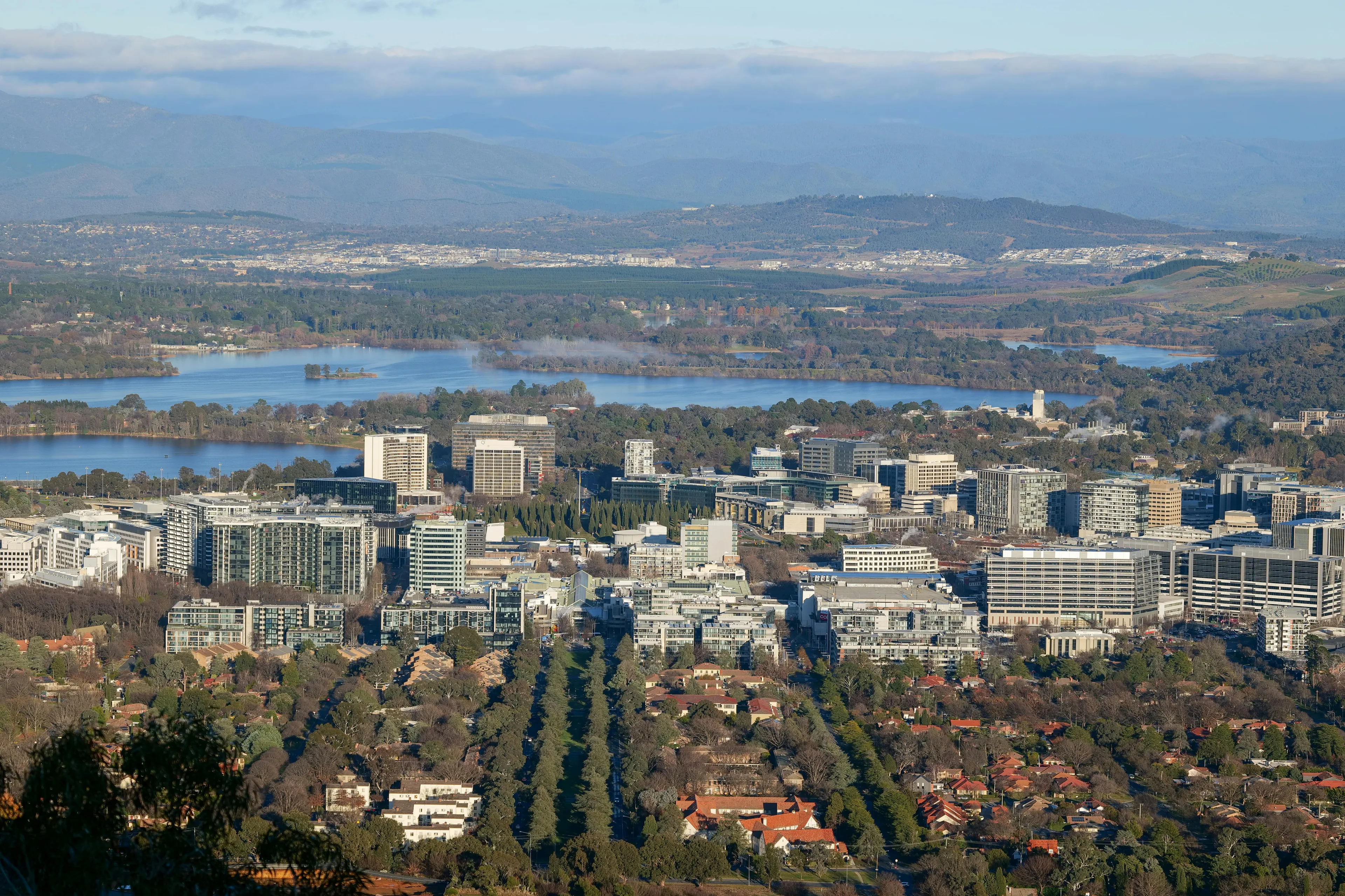 Aerial view of Canberra city with lakes and buildings, showcasing the capital of Australia in a clear sunny day.