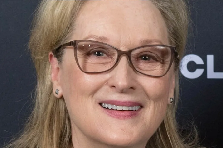 Close-up of an iconic actress wearing glasses, smiling at a pub quiz event challenge.
