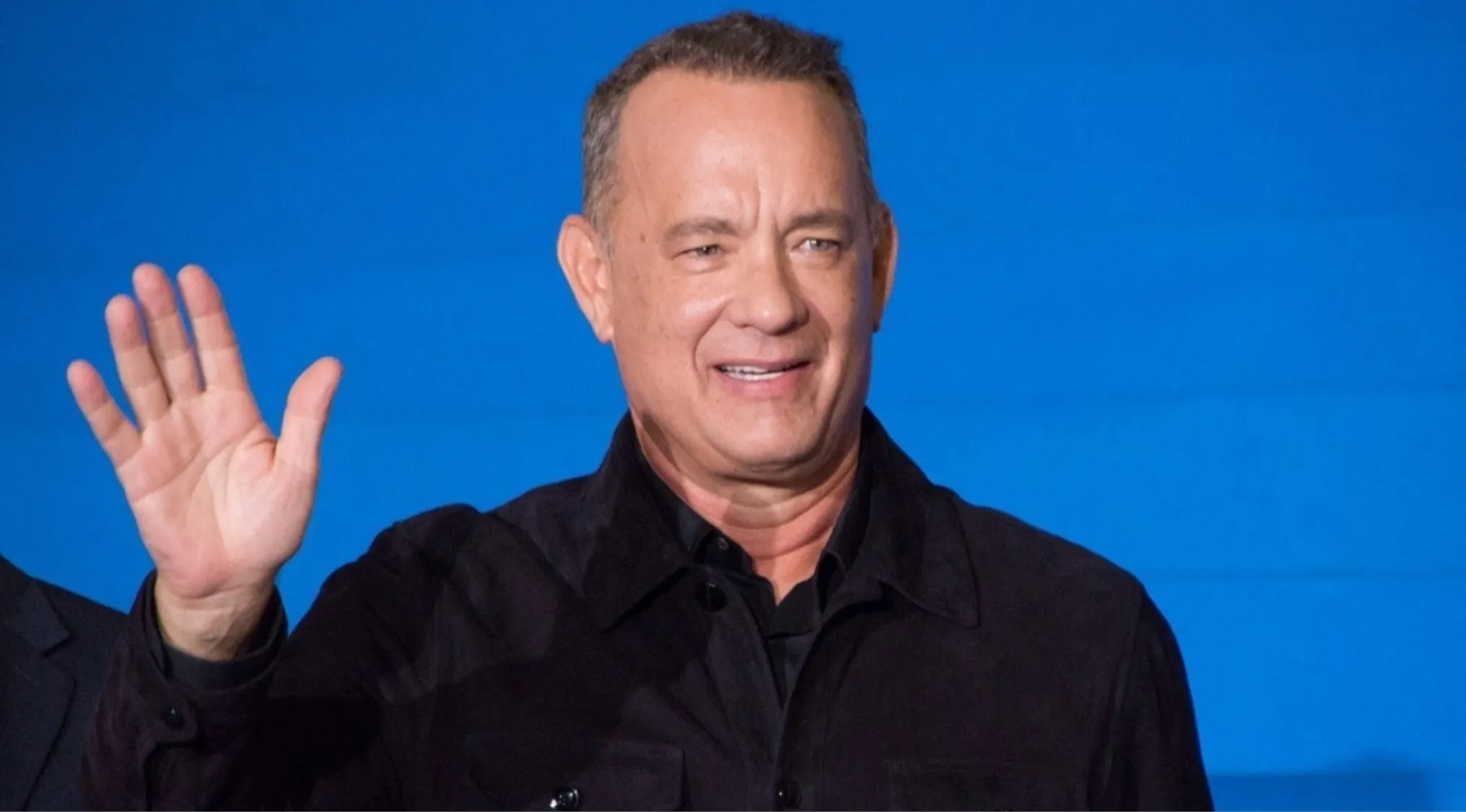 Famous person waving hand with blue background in Geography Challenge guessing the country visual hint game.