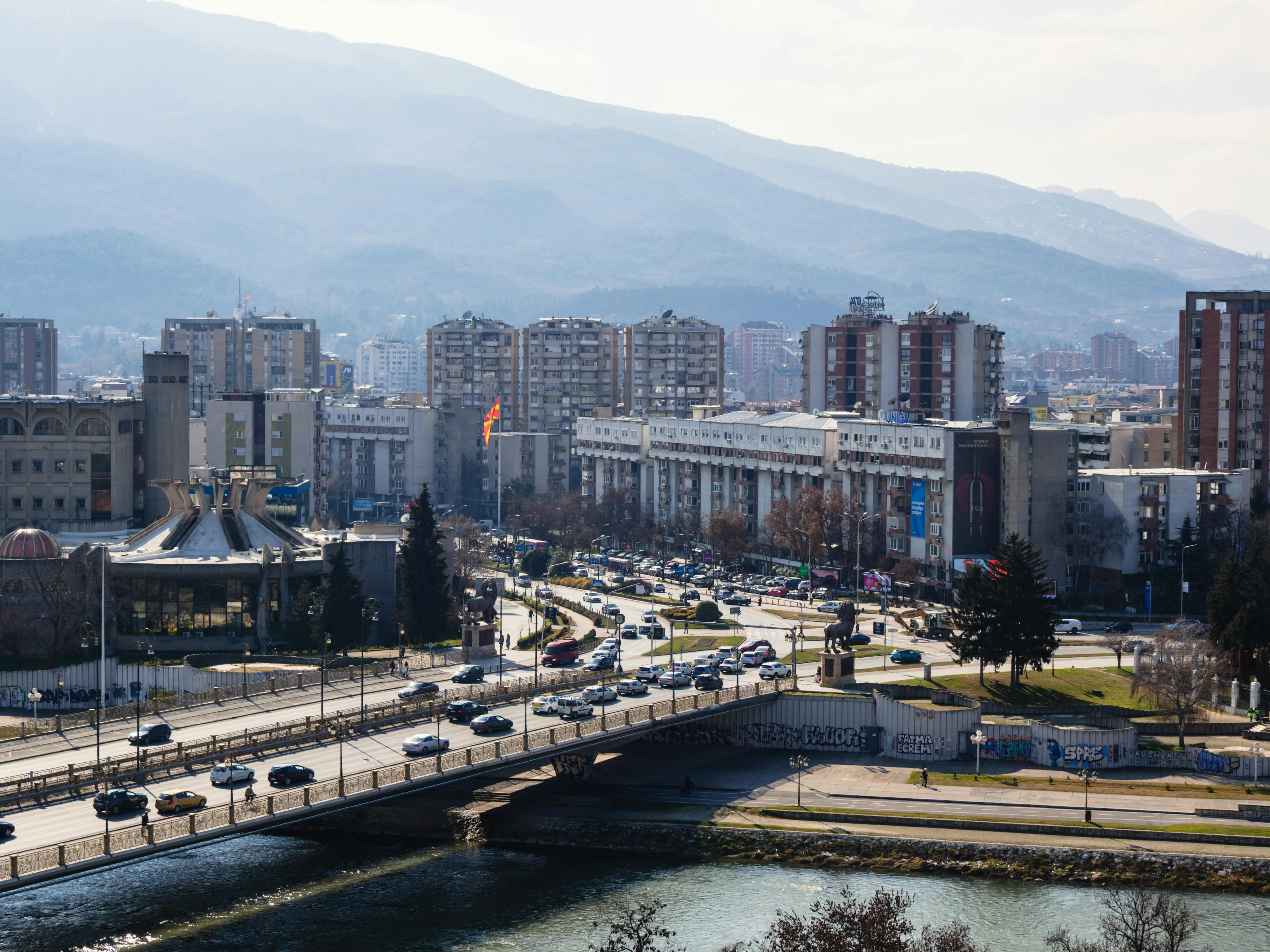 Cityscape of Skopje with traffic and buildings against a mountainous backdrop, highlighting the capital of North Macedonia.
