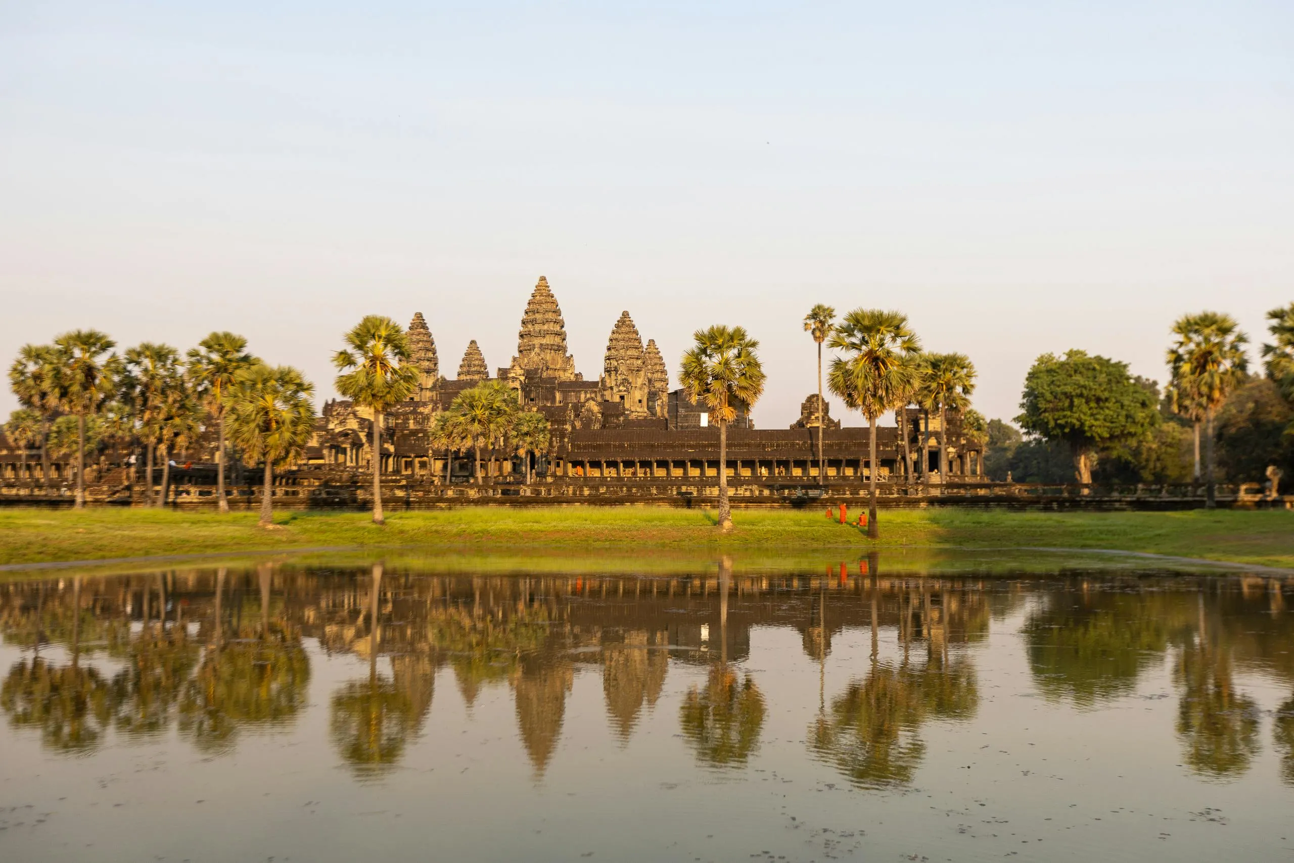 Angkor Wat temple reflected in a pond surrounded by trees, a geography challenge visual hint to guess the country.