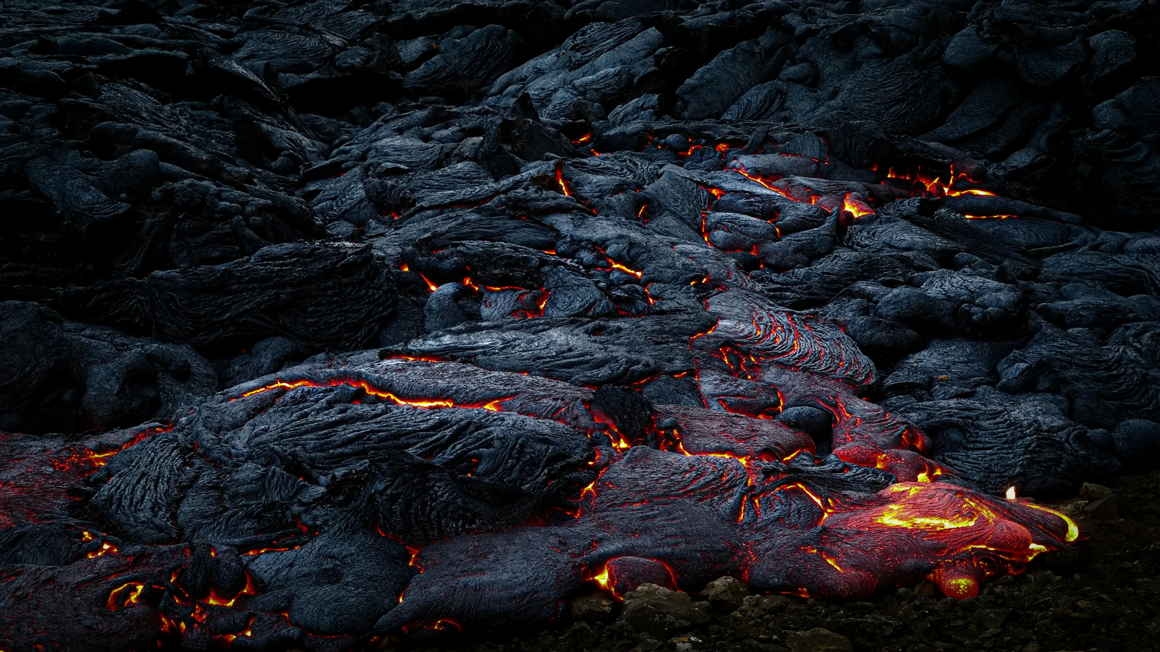 Molten rock beneath Earth’s surface glowing with red and orange heat as it cools into dark volcanic lava formations.