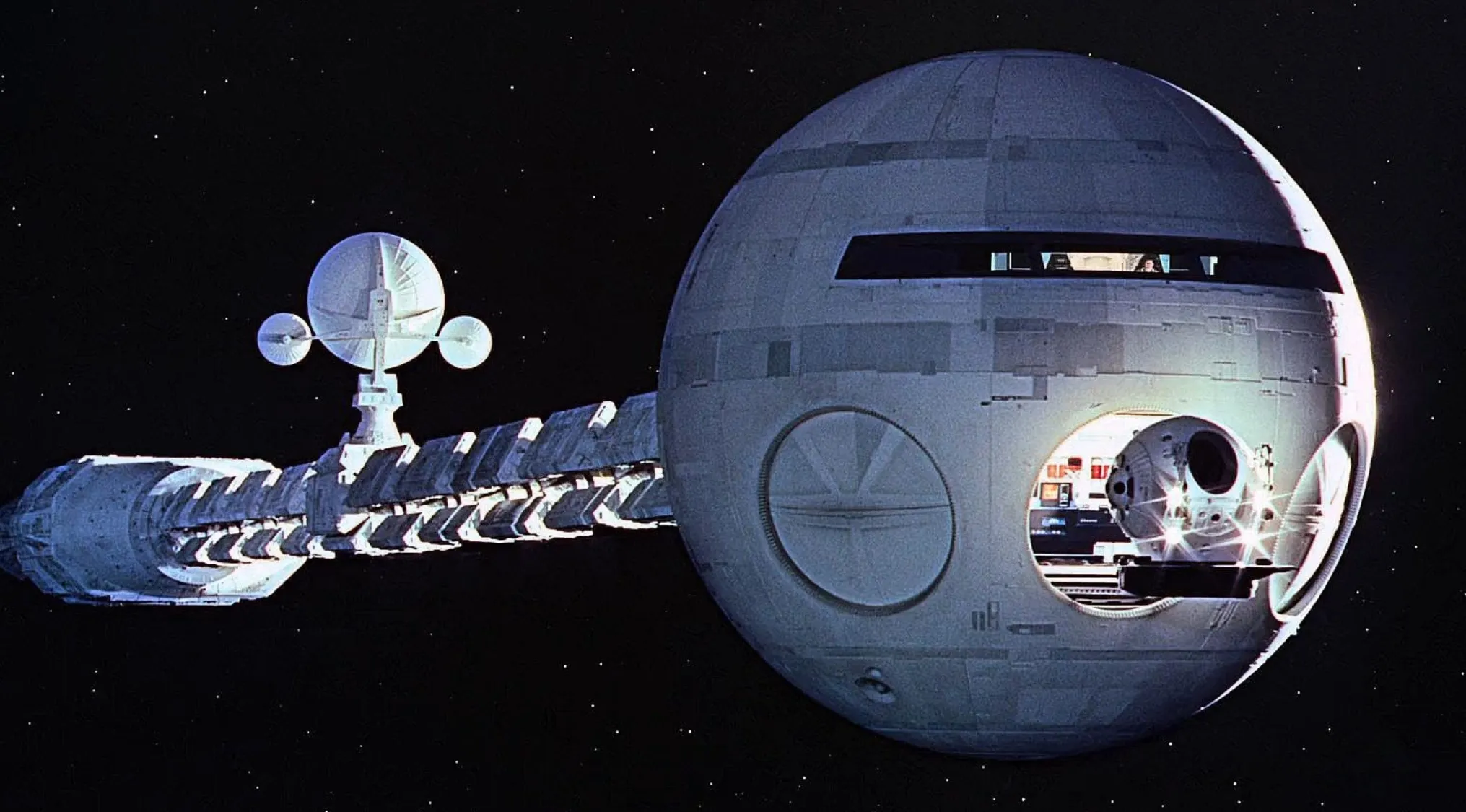 1960s movie scene showing a futuristic spaceship floating in space against a starry background.