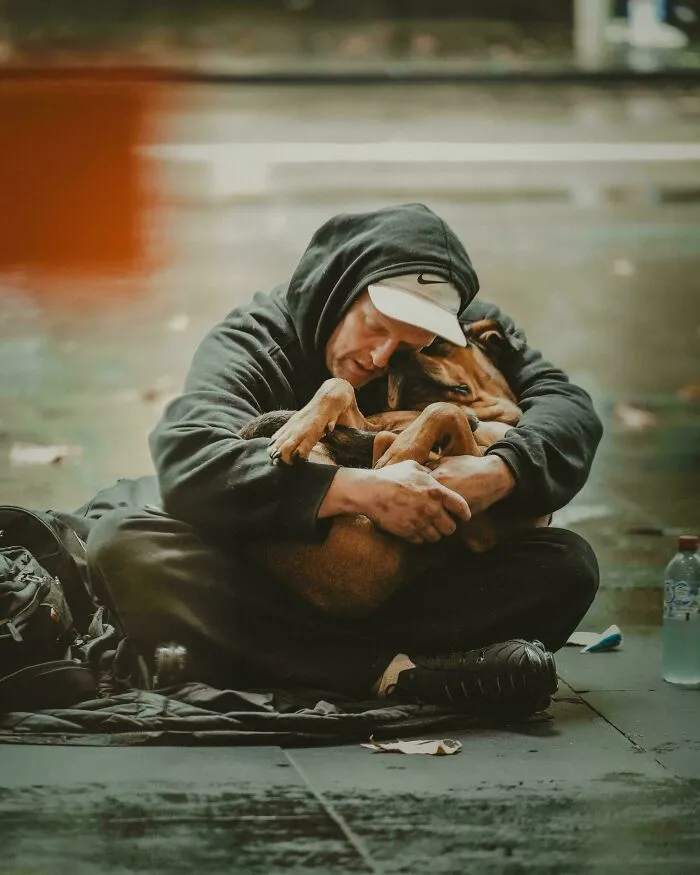 An emotional Accidental Renaissance portrait of a homeless man hugging his dog on the street.