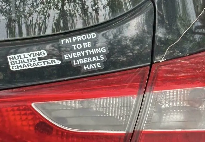 A car bumper features two funny, unfiltered bumper stickers: Bullying builds character and I'm proud to be everything liberals hate.
