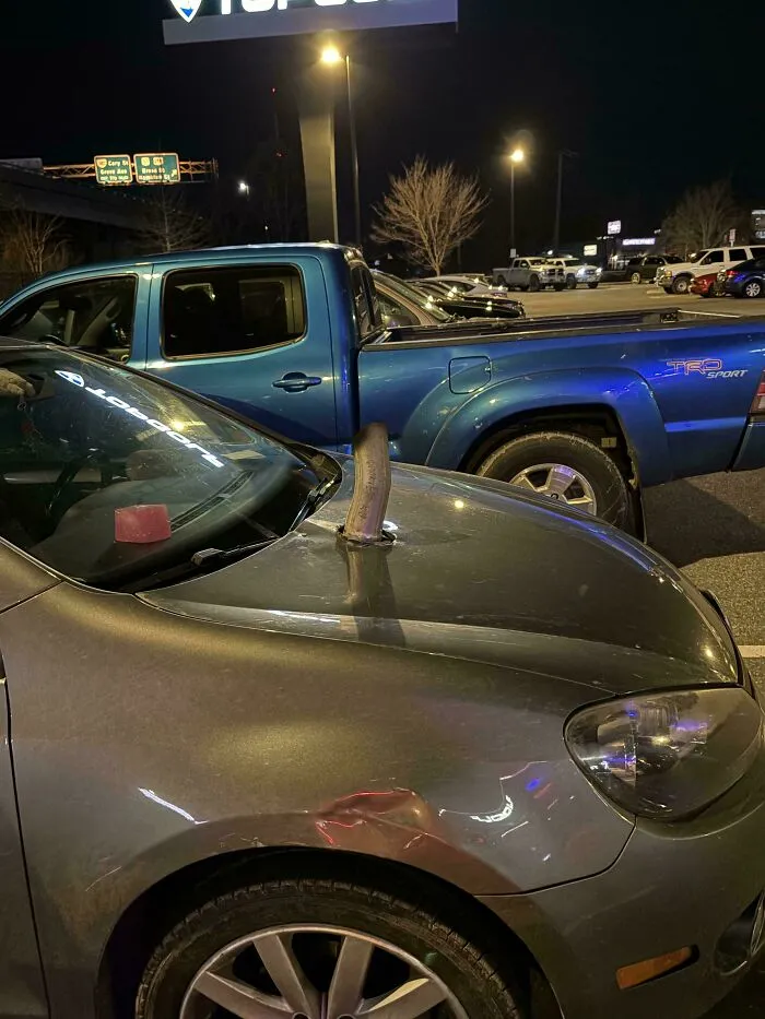 A grey car modified with an exhaust pipe sticking out of the hood, an example of questionable DIY projects.