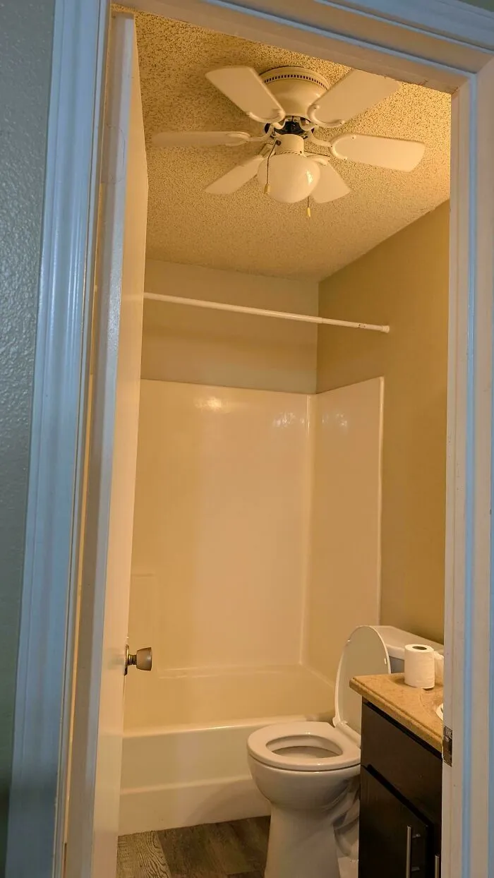 A ceiling fan questionable DIY project installed directly above a small bathroom shower tub.