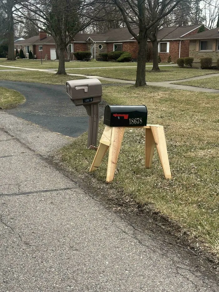 Black mailbox mounted on wooden sawhorse legs in a funny DIY project.