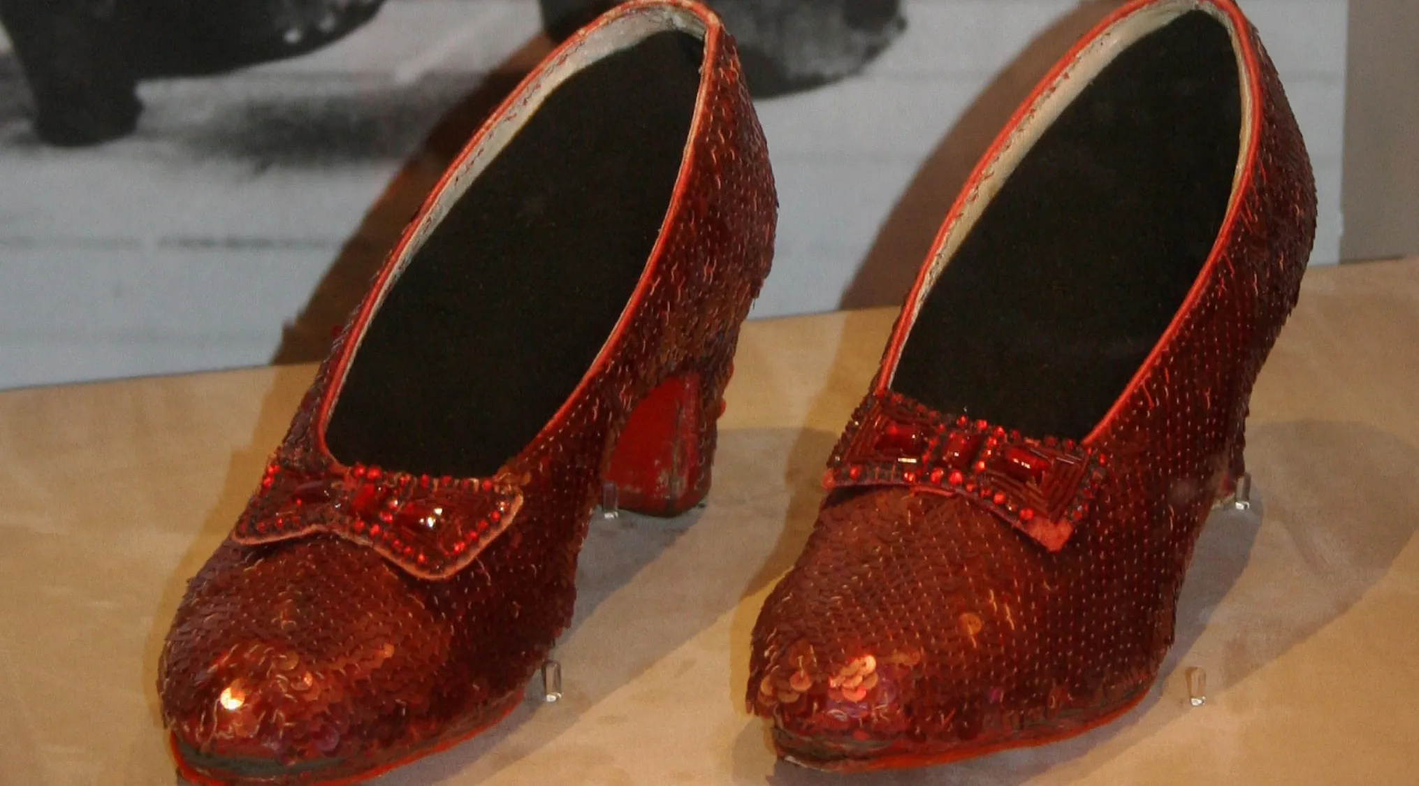 Ruby slippers worn by Judy Garland as Dorothy in The Wizard of Oz displayed in a glass case for guessing the sold price.