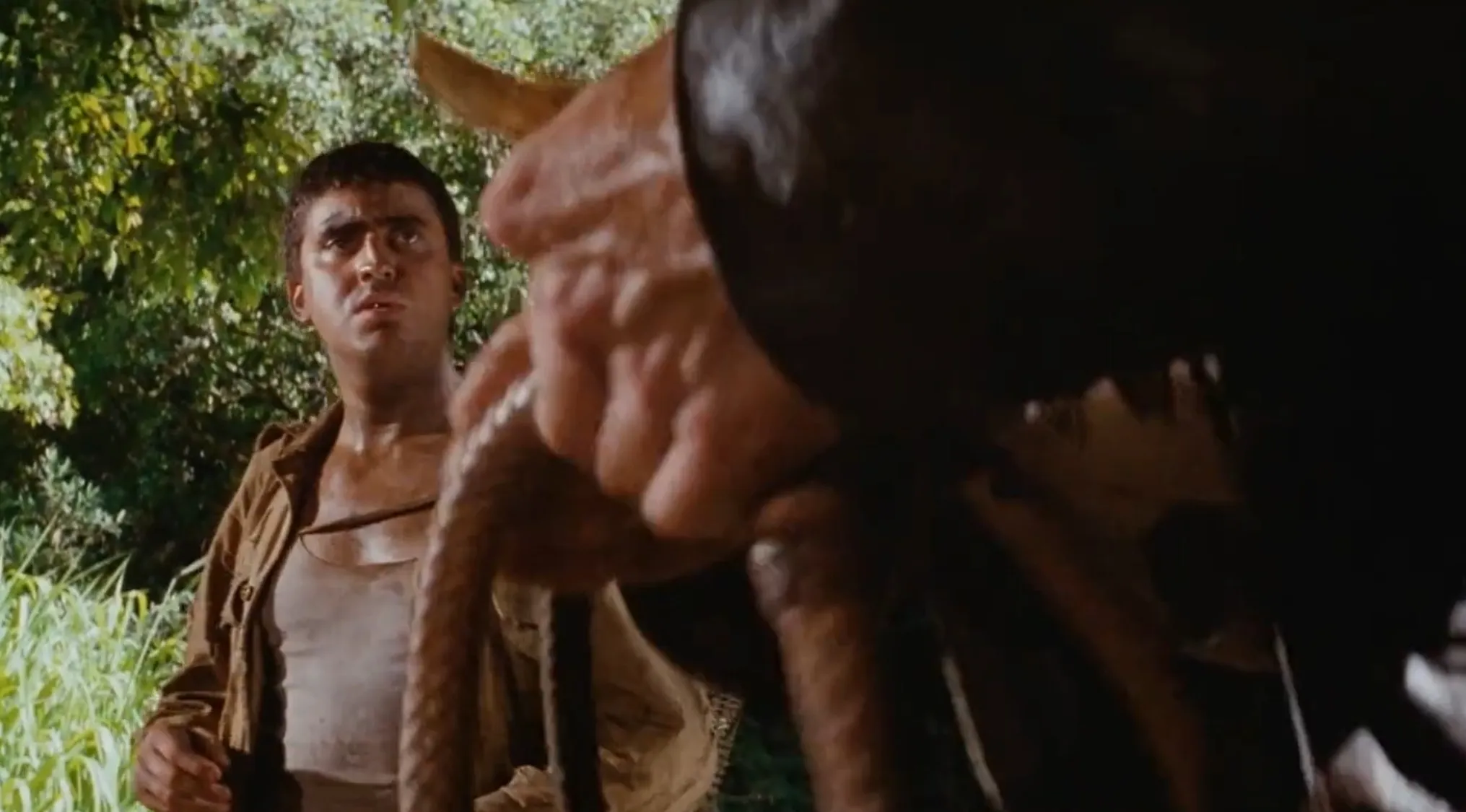 Man looking at a hand holding a bullwhip in a jungle setting related to Indiana Jones sold items price guess in 2025.