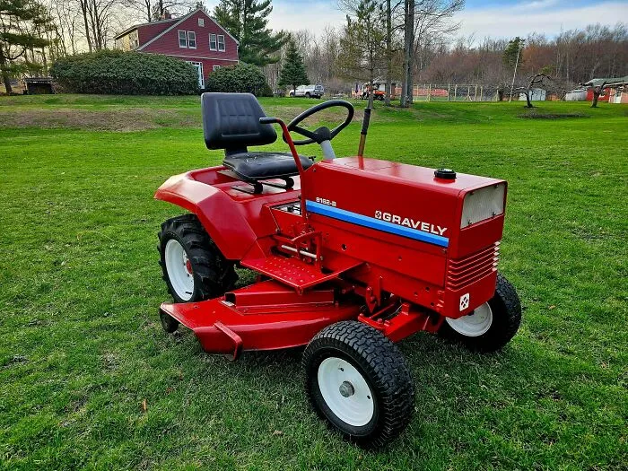 Vintage red Gravely riding lawn mower parked on a lawn, one of many old products that refuse to give up.