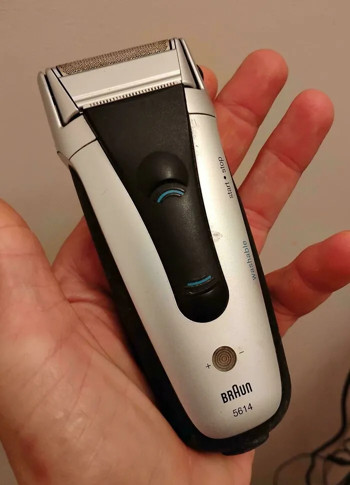 Hand holding an old Braun electric shaver, representing old products that refuse to give up.