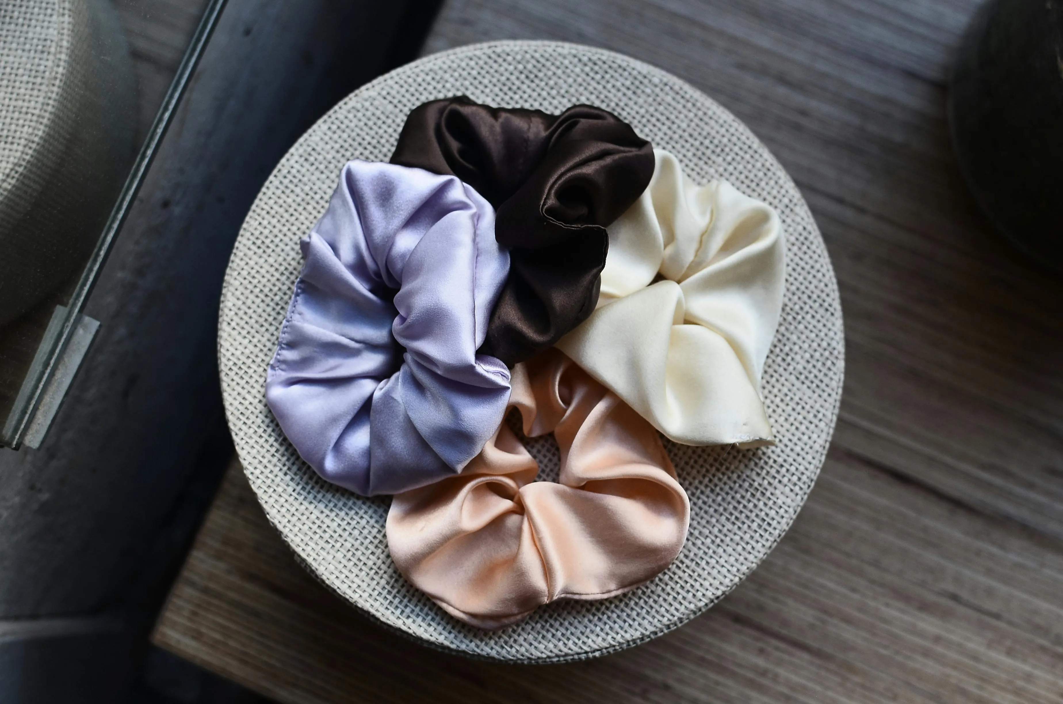 A collection of colorful silk scrunchies displayed on a round fabric-covered surface, perfect party favors.