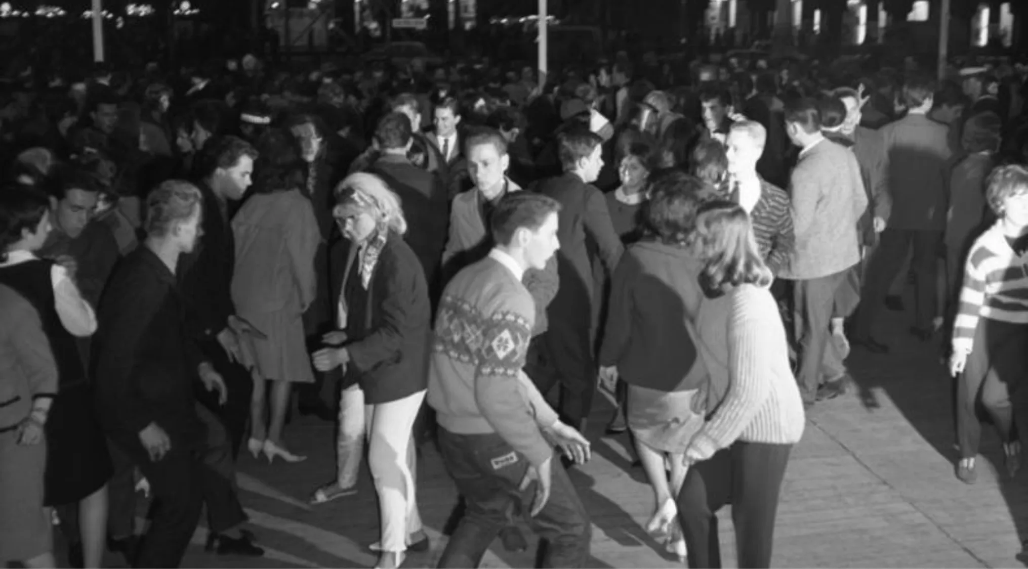 Crowd of young people dancing at a large social gathering showcasing the popular dance craze of the early 60s.