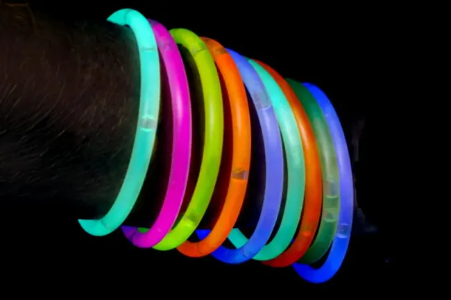 Glow-in-the-dark bracelets glowing brightly in various colors worn as favorite party favors on a wrist.
