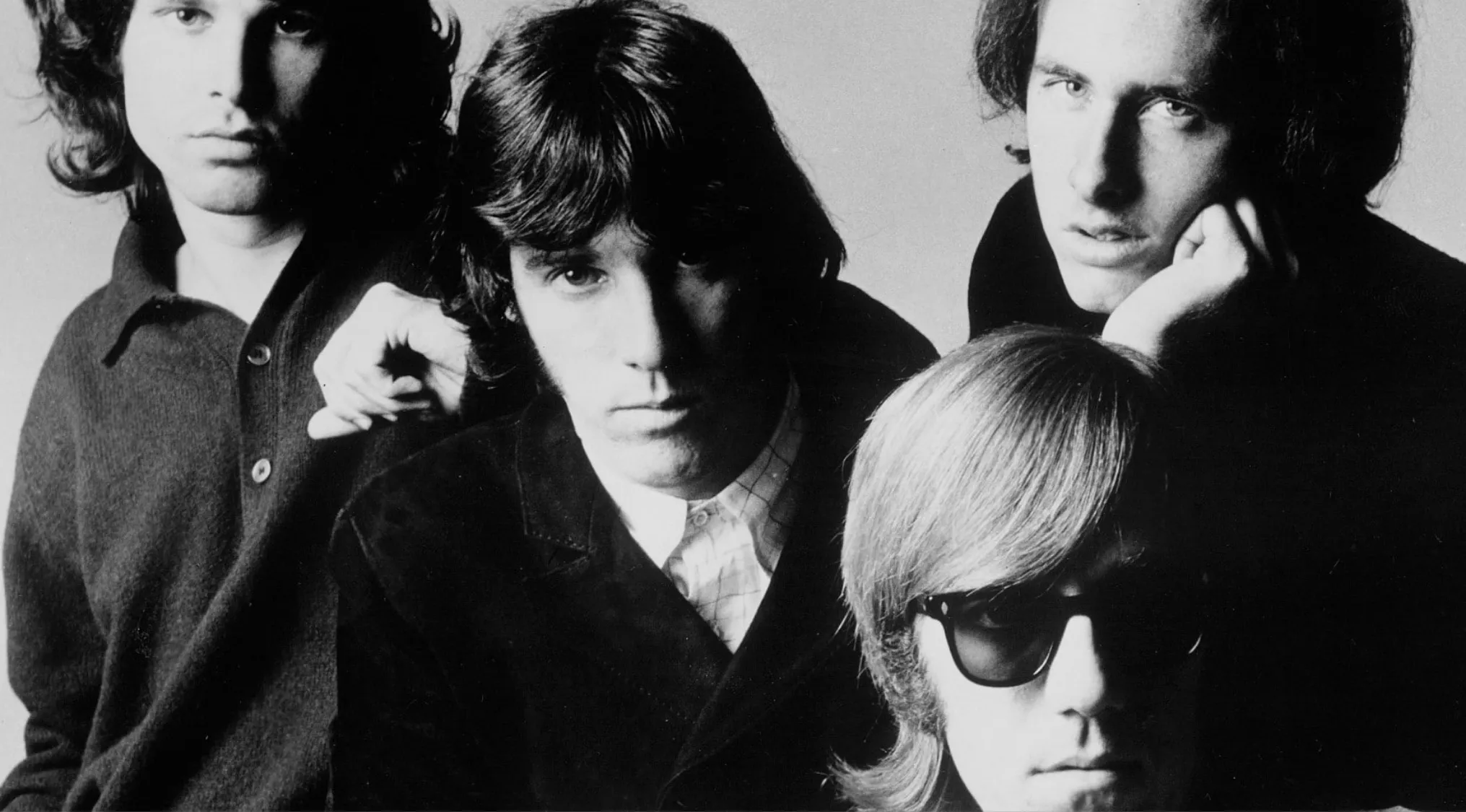 Black and white portrait of the band The Doors with four members in close-up, classic rock group photo.
