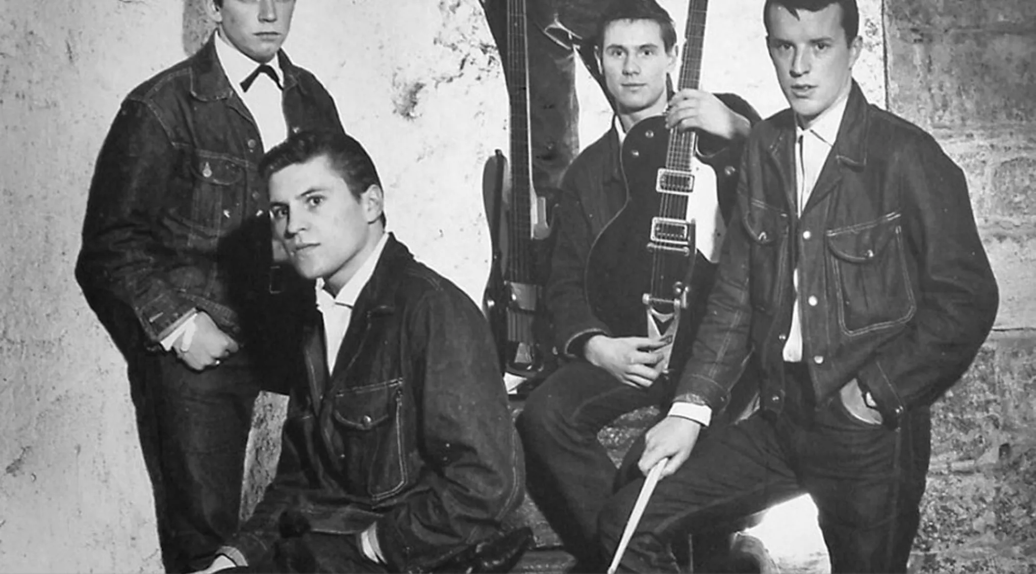 Black and white photo of a 1960s band posing with guitars, related to the song I Can't Get No Satisfaction writers.