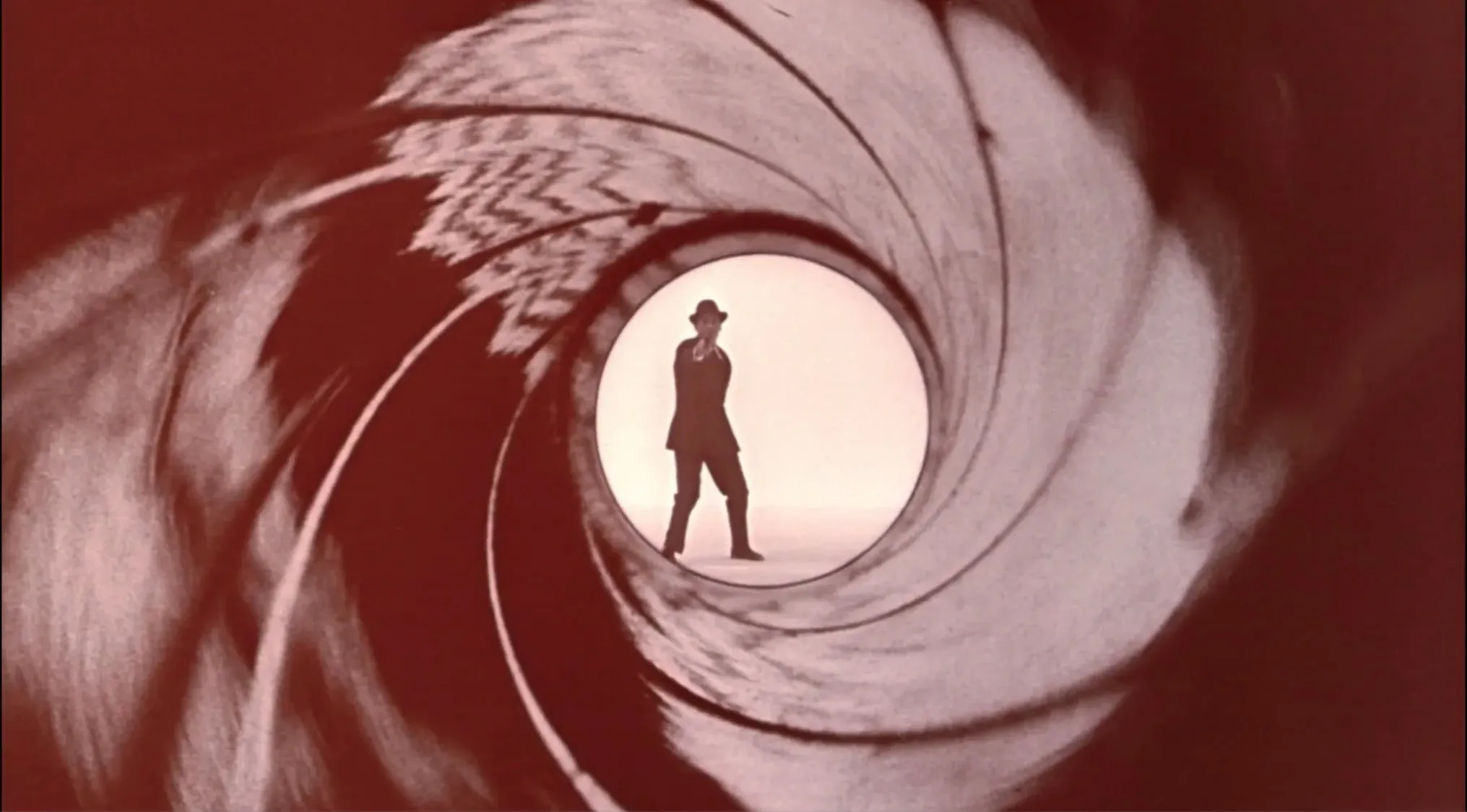 Silhouette of a man in a suit and hat, iconic spy film series imagery.
