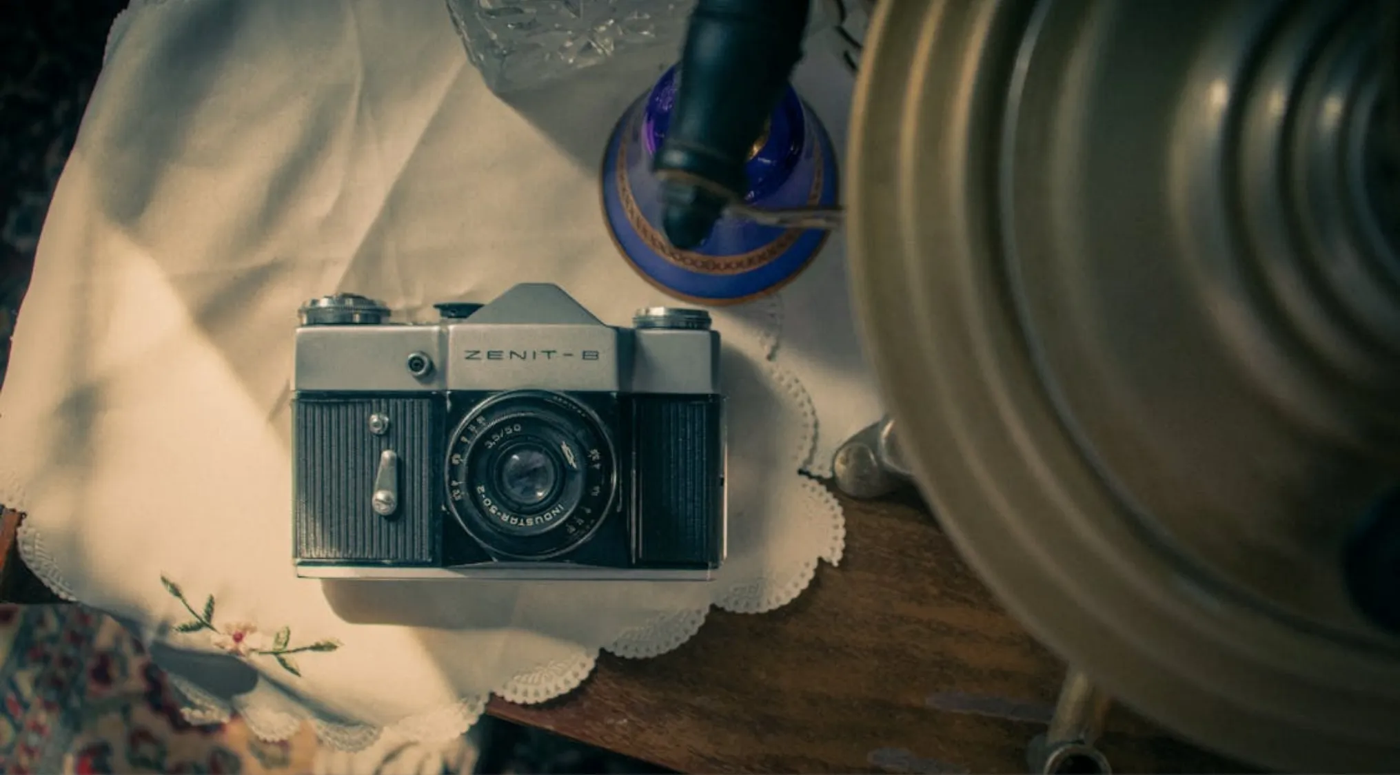 Vintage Zenit-B camera resting on a lace doily, representing popular camera brands for family moments in the 60s.