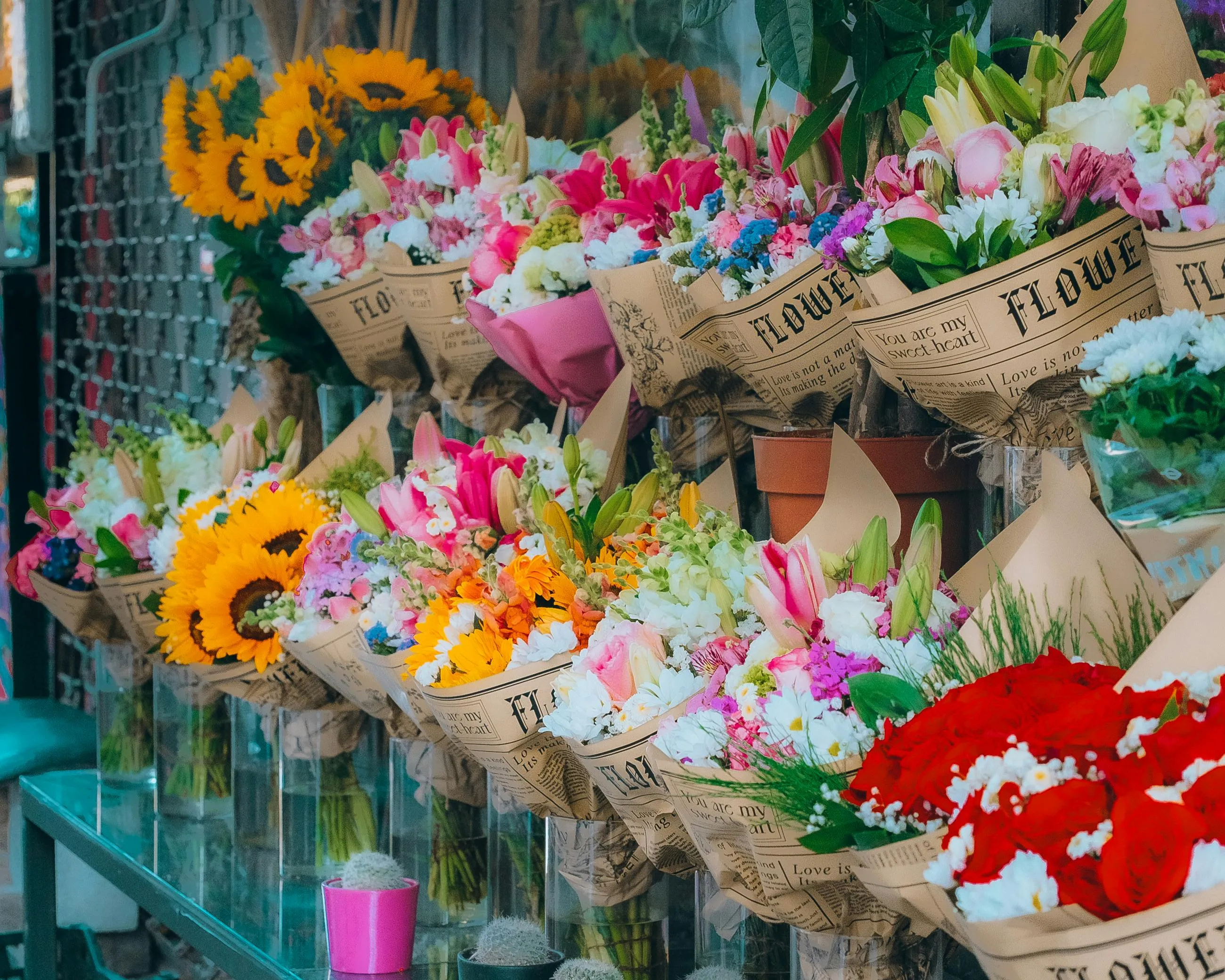 Colorful bouquets displayed in a flower shop featuring sunflowers, roses, lilies, and mixed seasonal blooms.