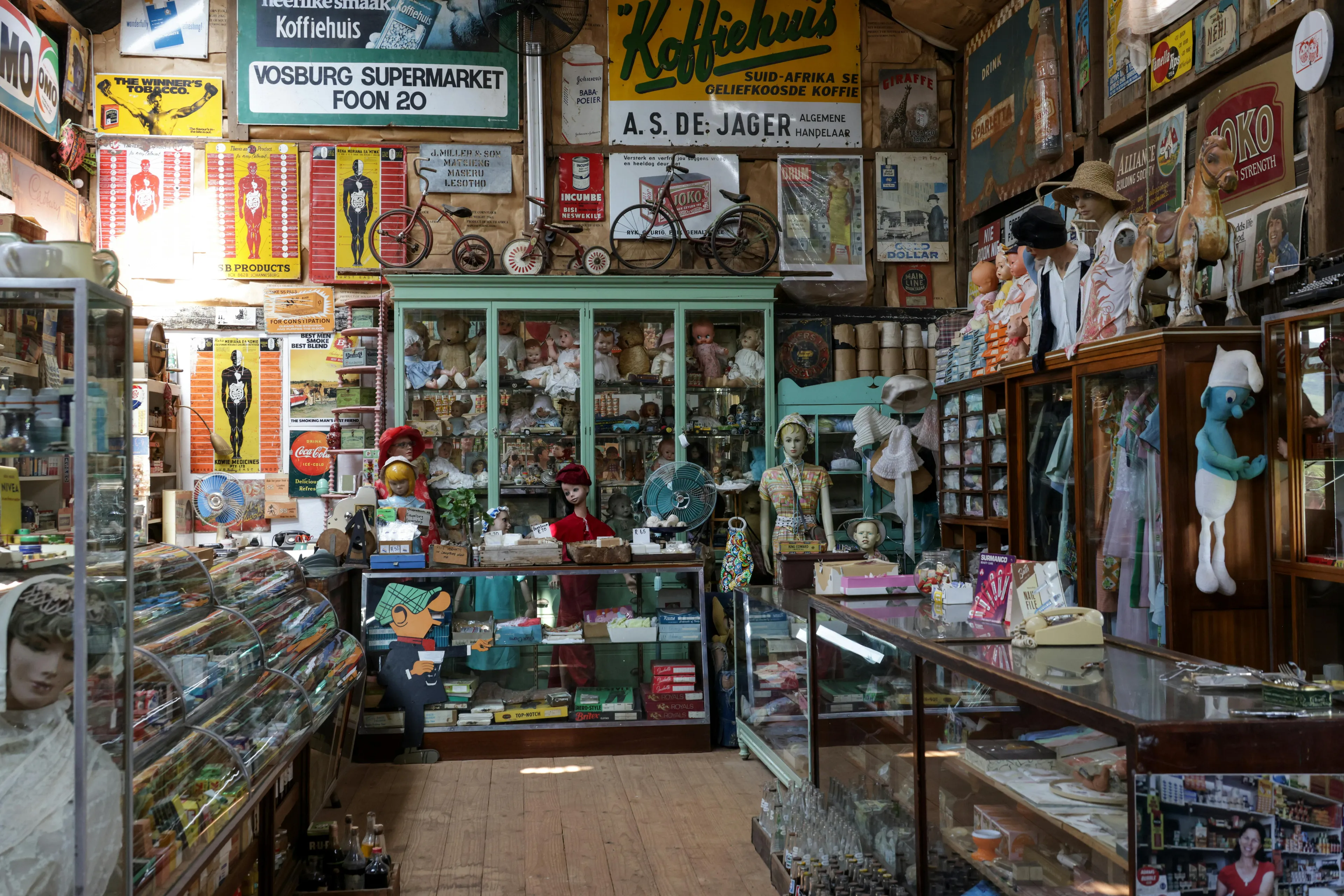 Interior of an antique shop filled with vintage items, old signs, mannequins, and collectibles on wooden floors.