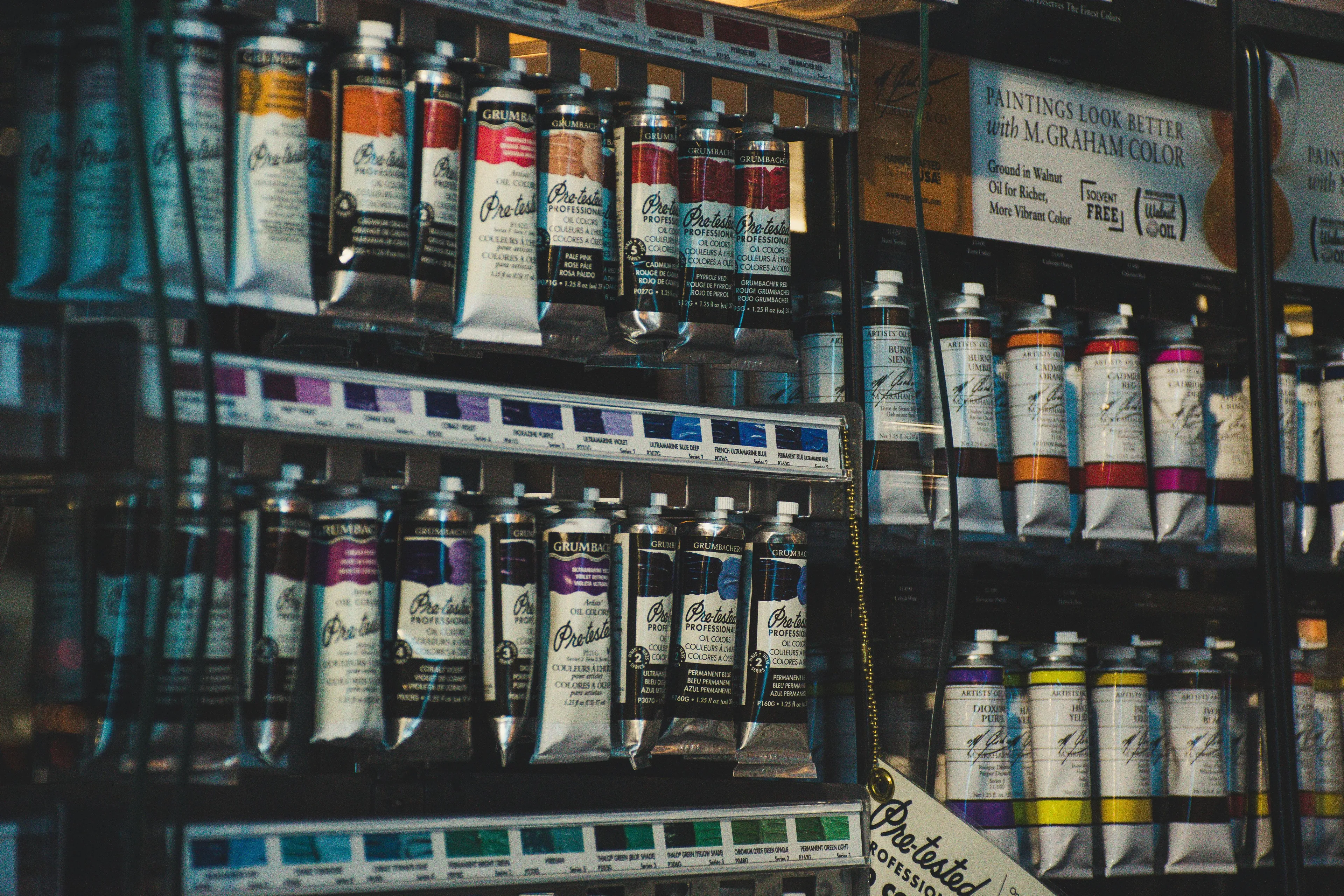 Shelves stocked with tubes of paint and art supplies in a well-organized art supply store display.