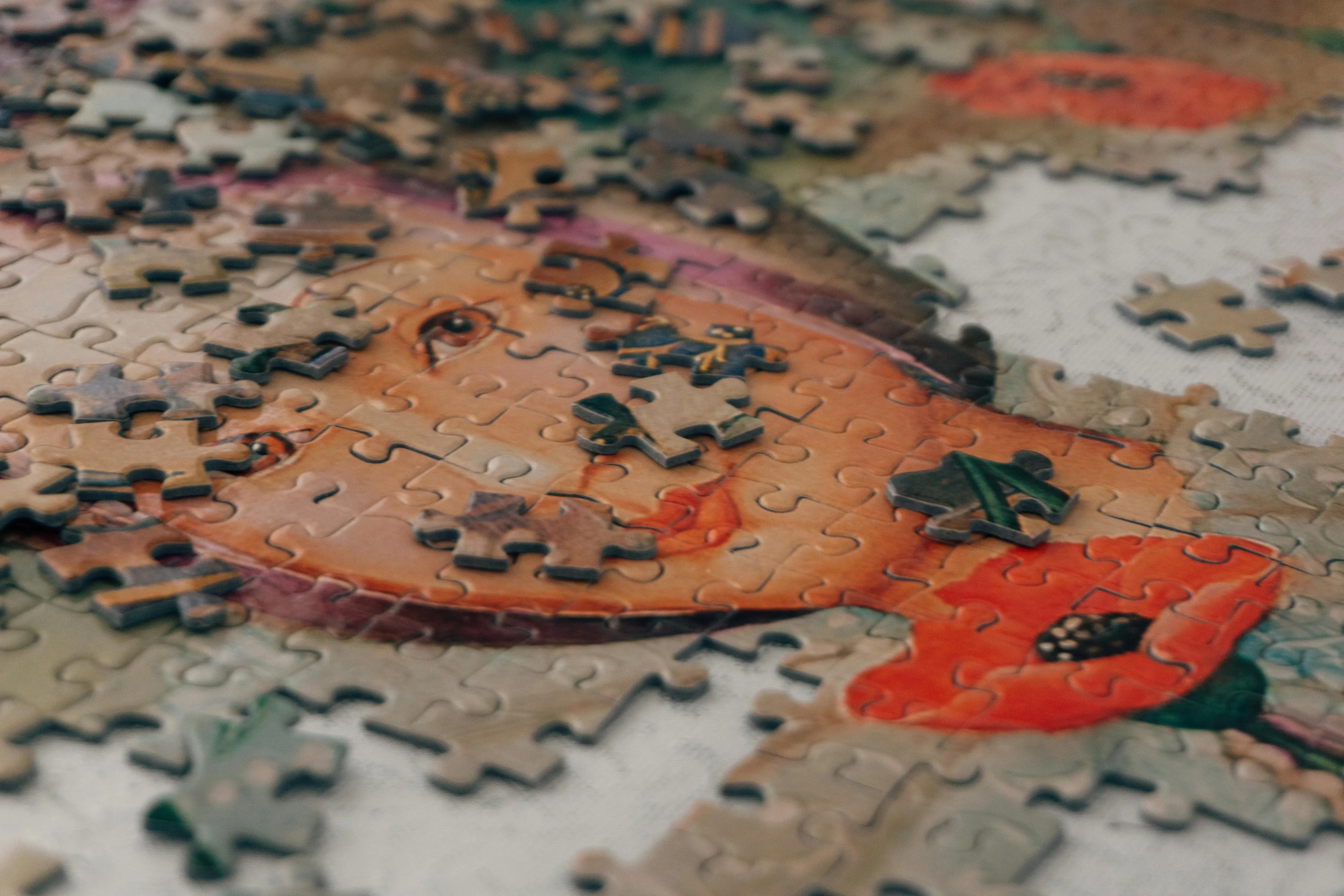 Close-up of a partially completed puzzle featuring a painted portrait with scattered puzzle pieces on a flat surface.