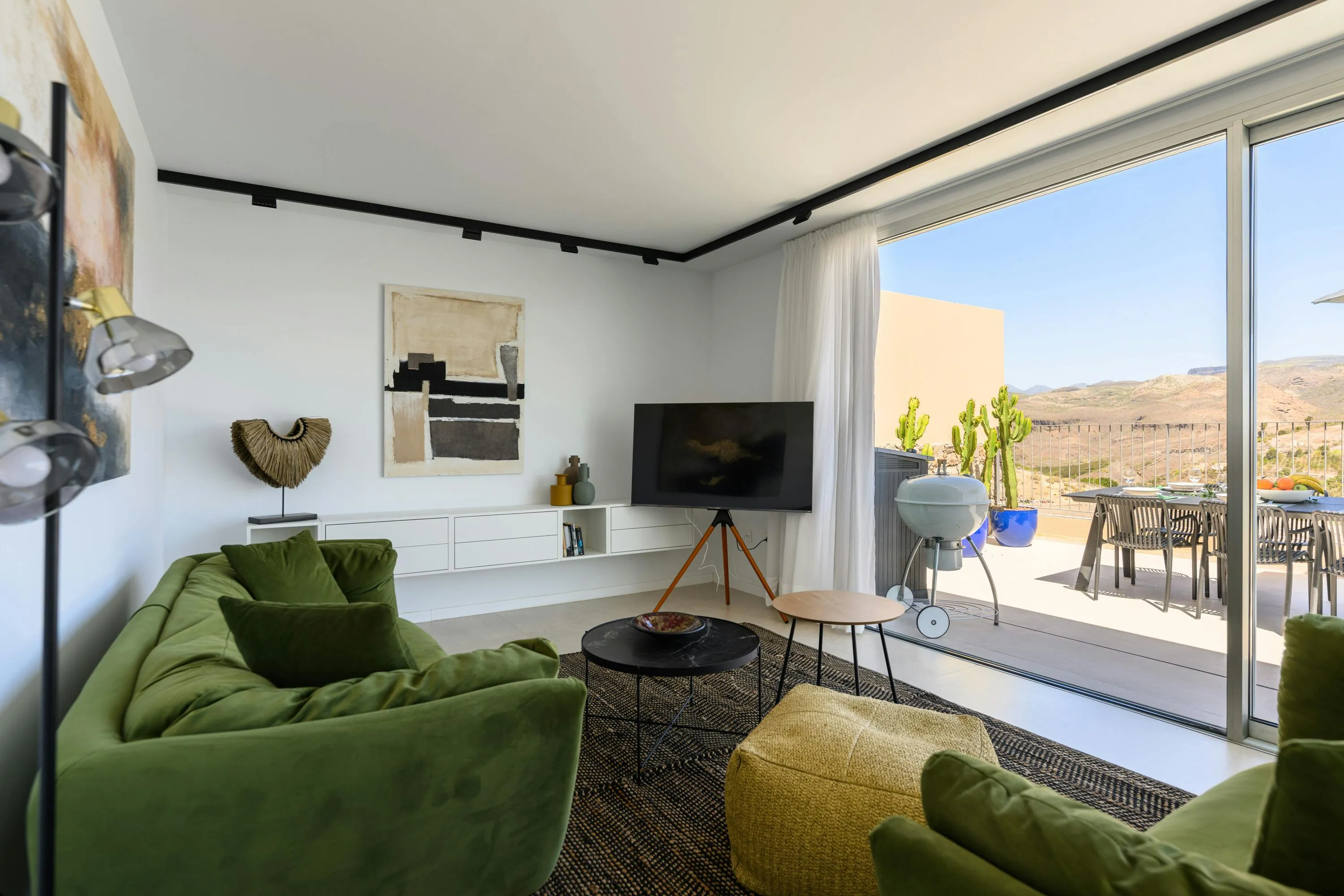 Modern living room with green sofas, a TV, and a patio view, showcasing the ideal home for a comfortable lifestyle.