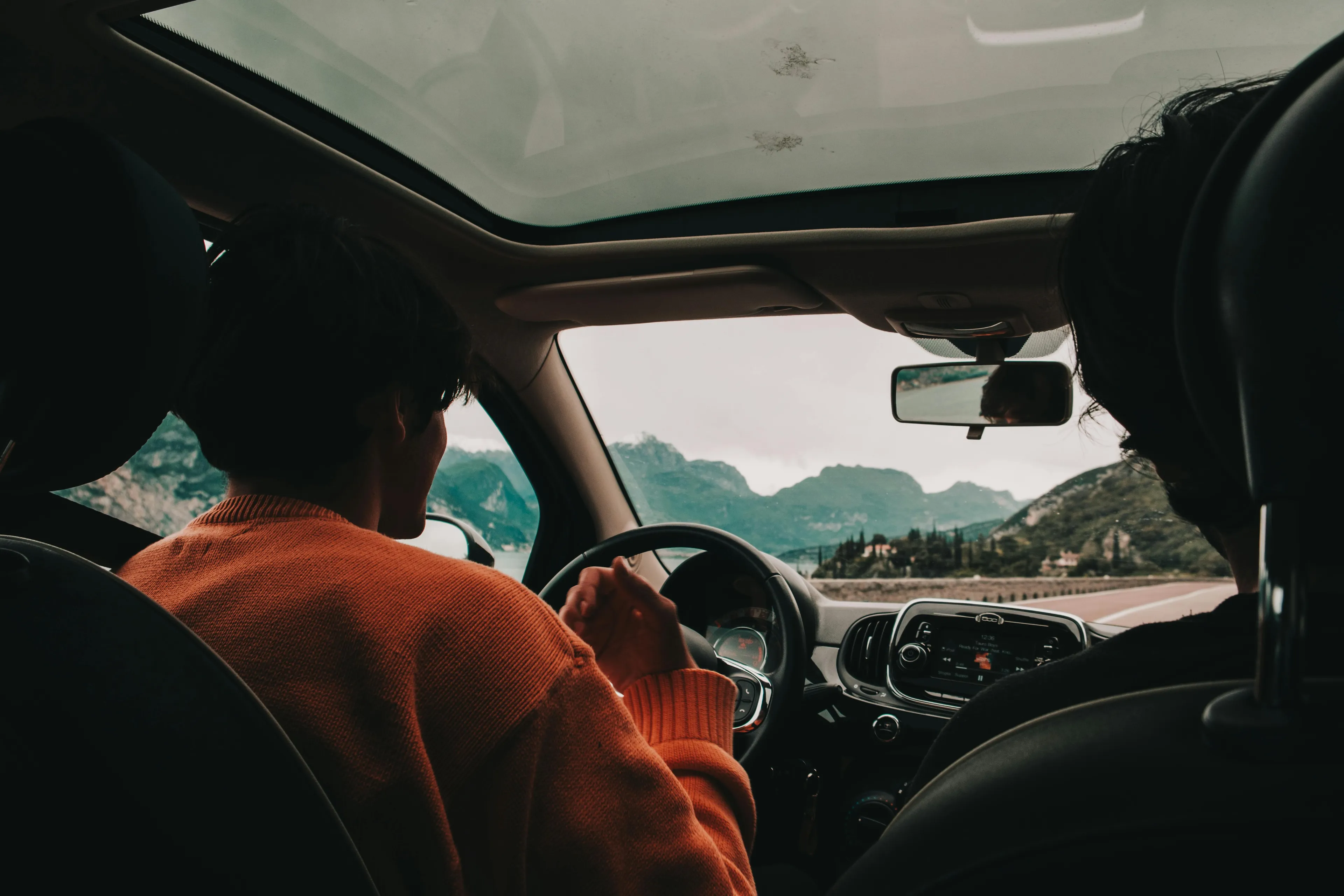 Two people inside a car driving through mountains, showcasing a favorite mode of transportation for a spontaneous trip.