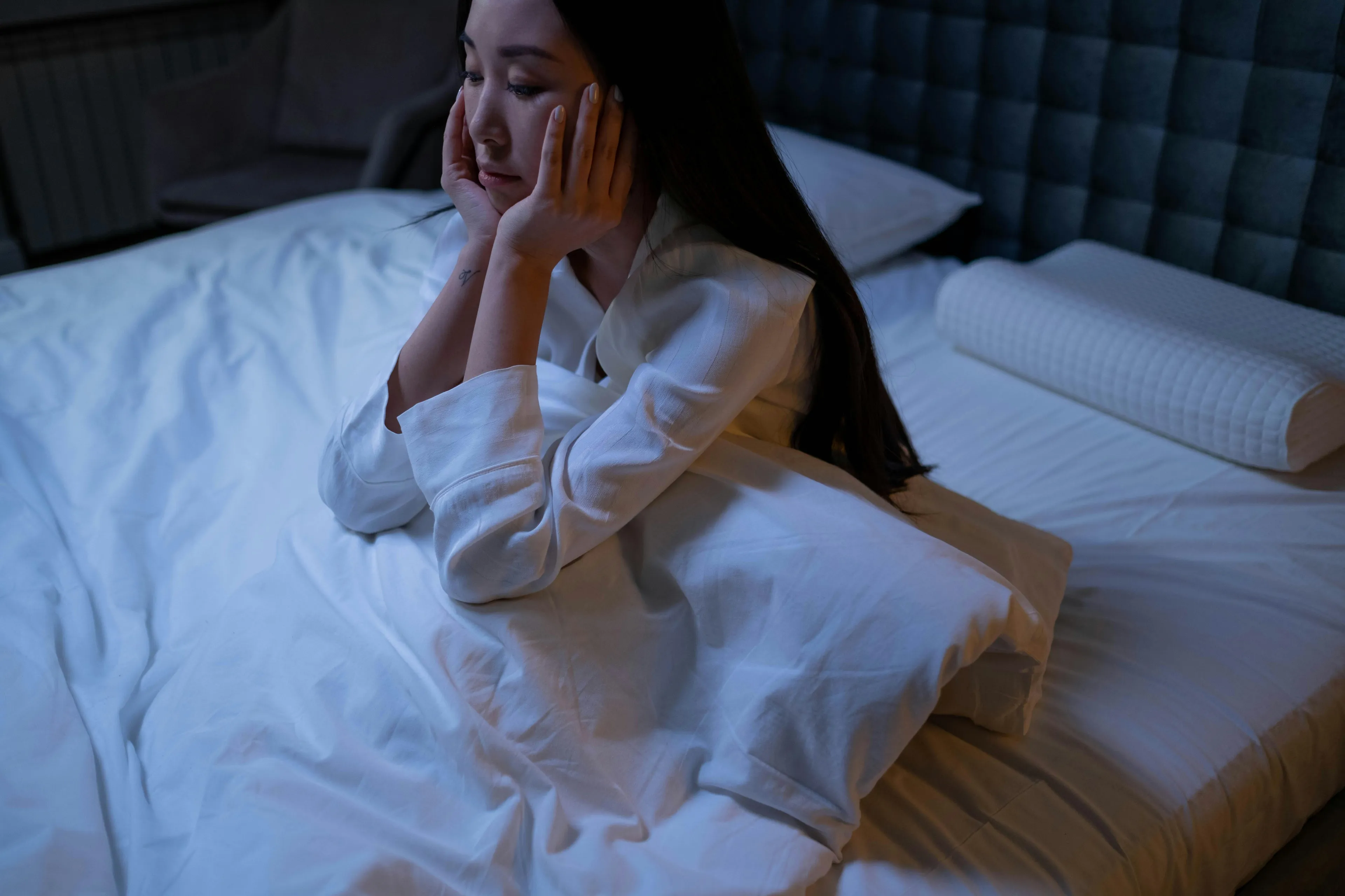 Woman struggling with sleeplessness sitting on bed at night, reflecting on where life would be set.