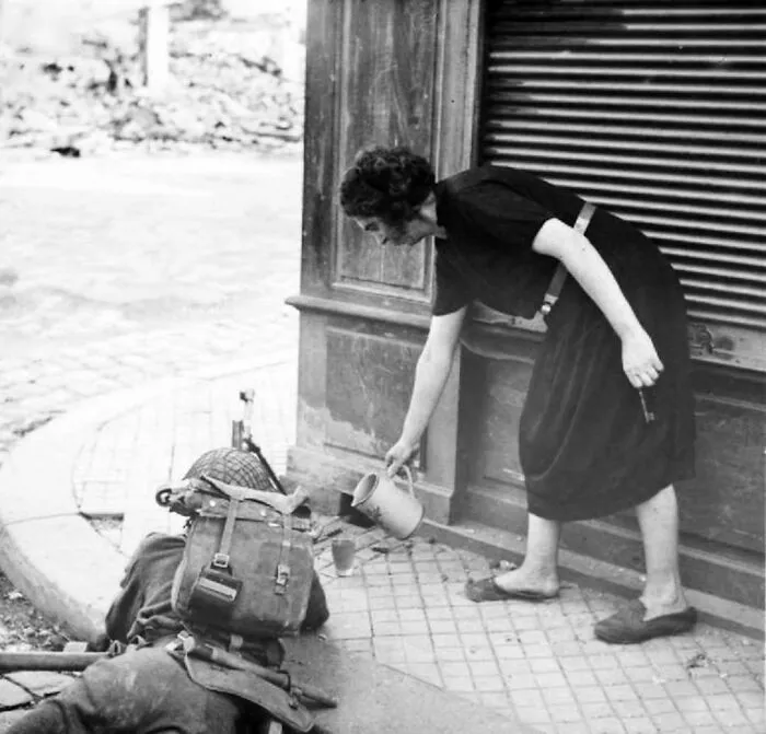 A French Woman Pouring Cider For A British Bren Gunnėr In Lisieux, France. August, 1944