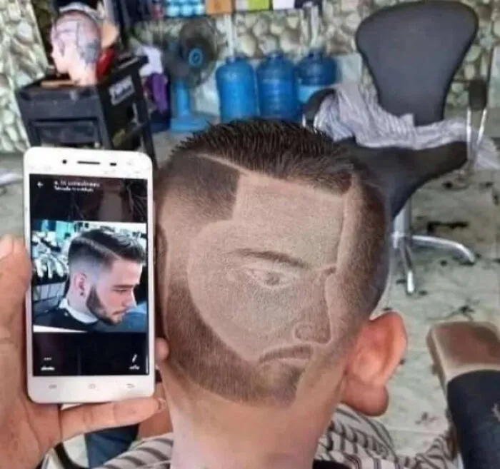 A man with an unfortunate haircut styled with a face profile on the back of his head.