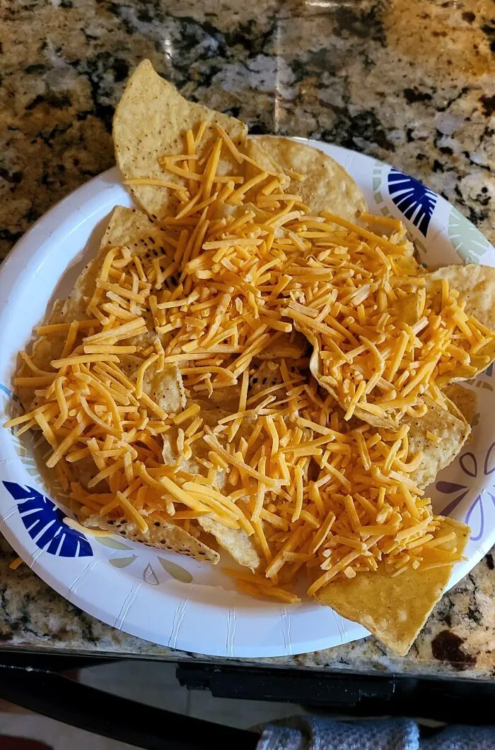 Plate of tortilla chips topped with shredded cheddar cheese, illustrating true colors of friends in a humorous way.