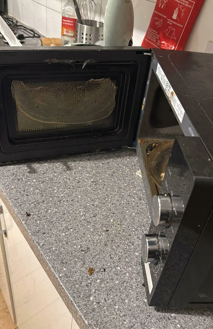Damaged microwave door with burnt marks and stains on kitchen countertop showing true colors of friends' neglect.