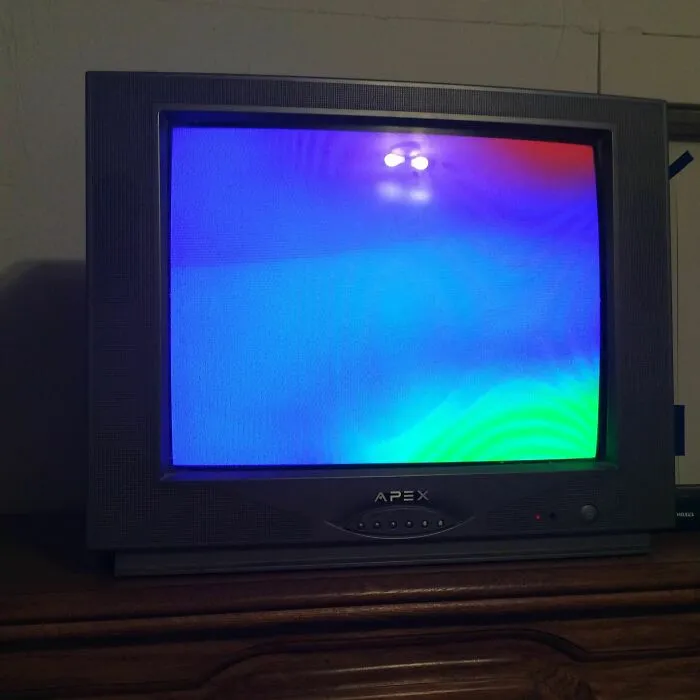 Old Apex CRT TV displaying a colorful distorted screen, still feels fake but showing real visual glitch effects.