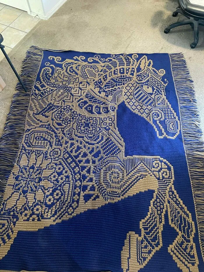 Large crocheted blanket featuring an intricate horse design in blue and beige