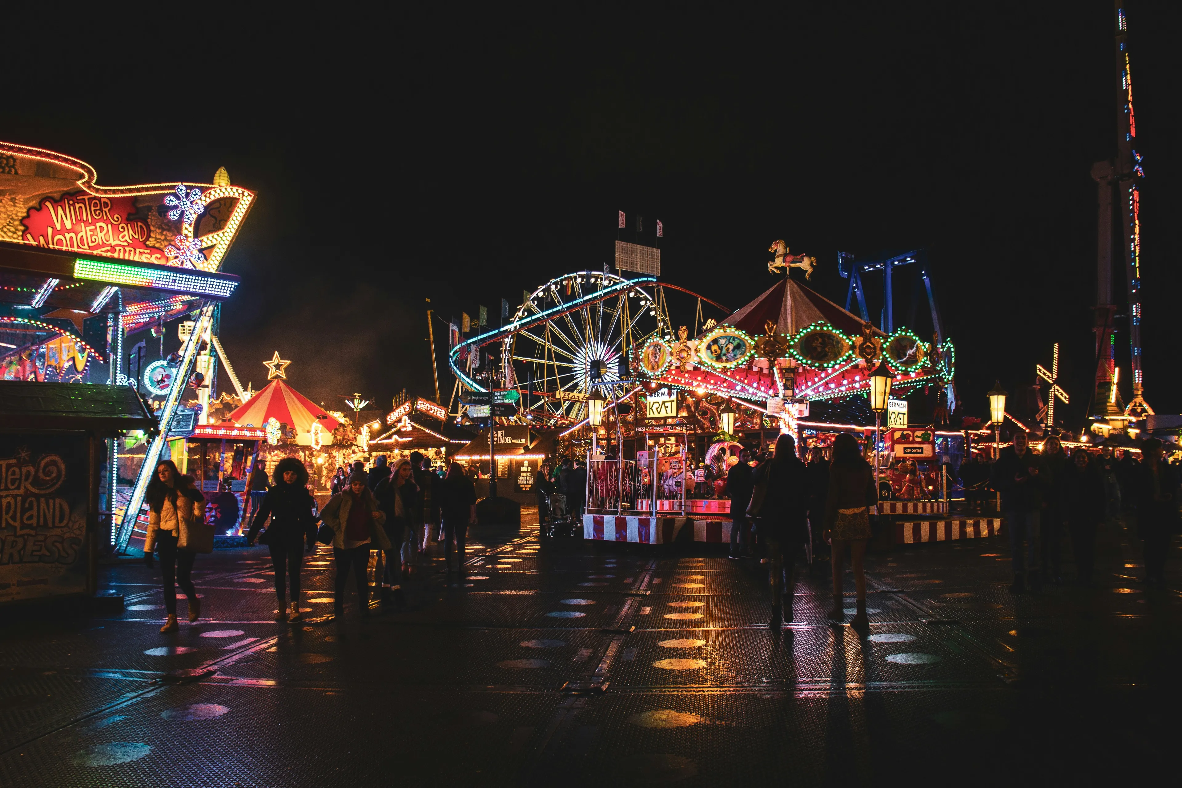 Colorful carnival attraction at night with crowds of people enjoying rides and lights under the dark sky.