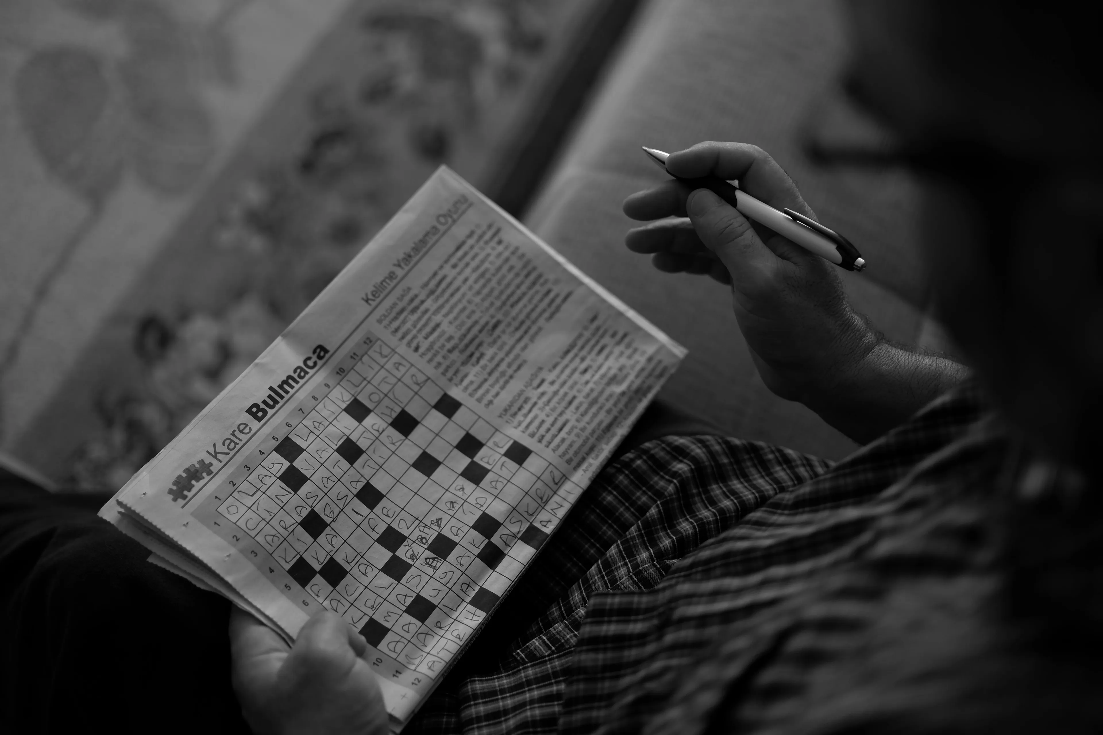 Person holding a pen and solving a crossword puzzle, contemplating what job matches your soul concept.