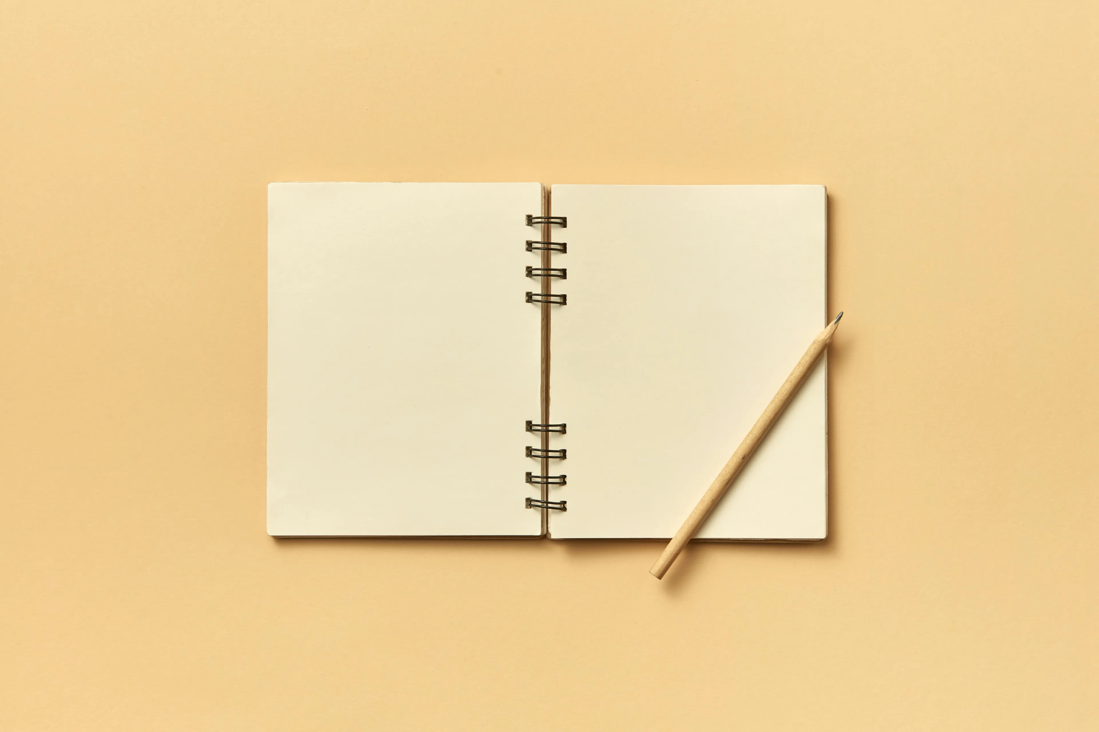 Blank notebook open on a beige background with a wooden pencil, symbolizing job matches and creative potential.
